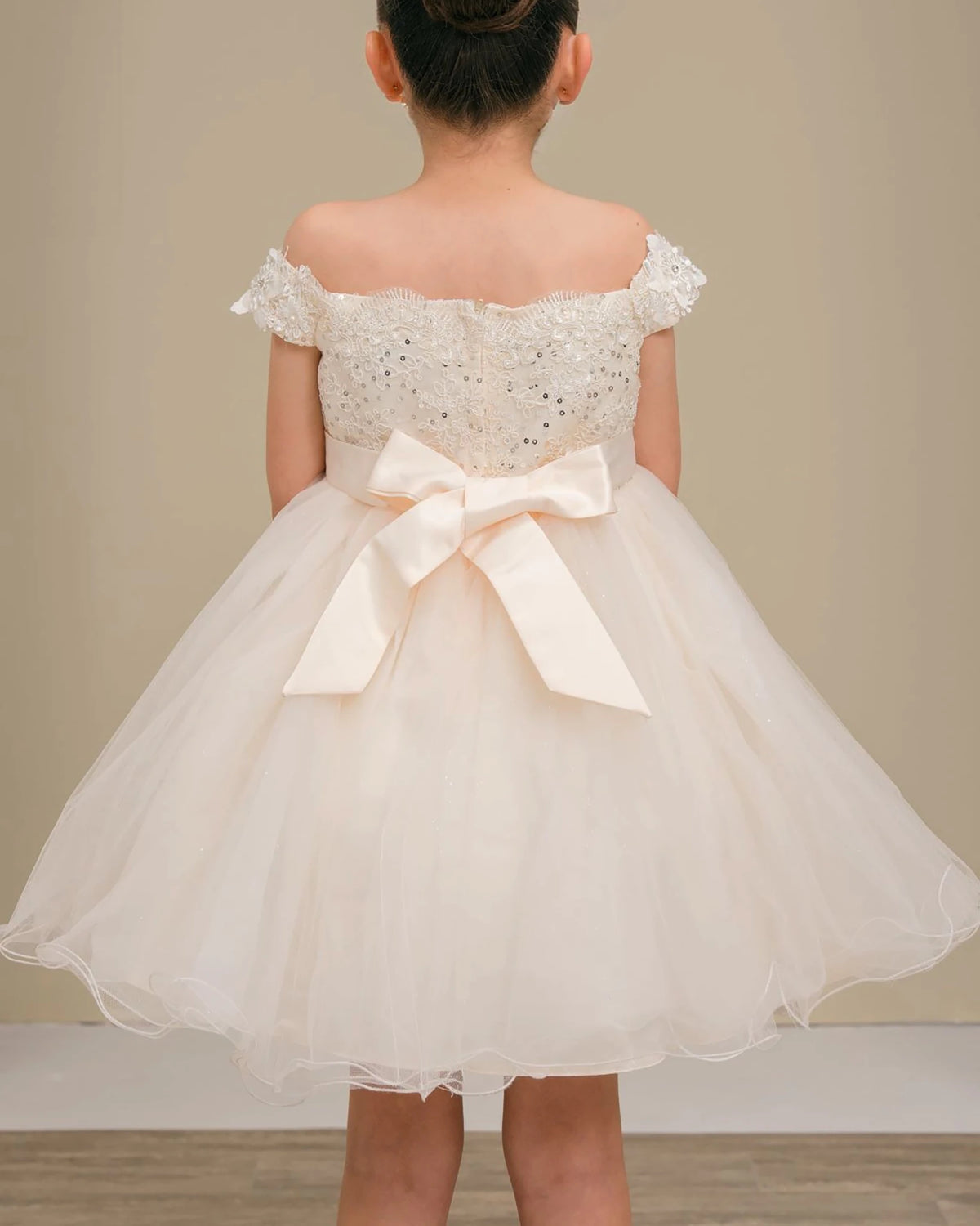 Champagne lace flower girl dress with a large bow.