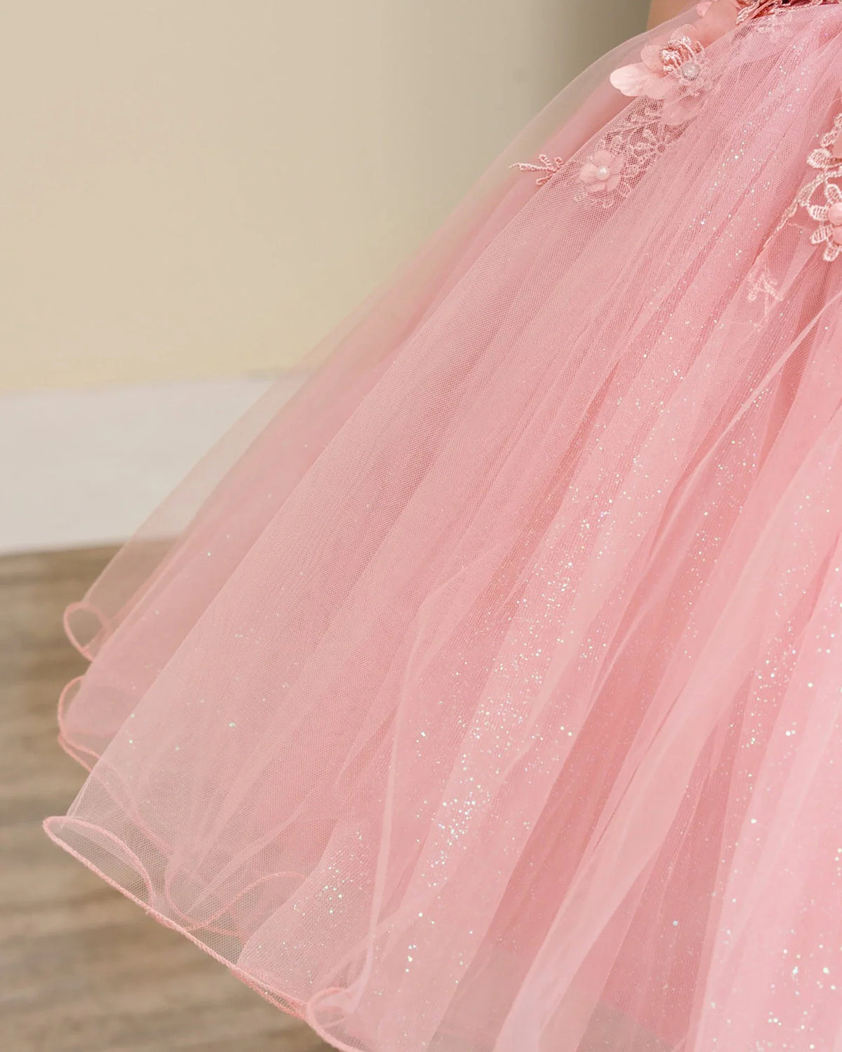 Close-up of a dusty rose flower girl dress with tulle and floral details.