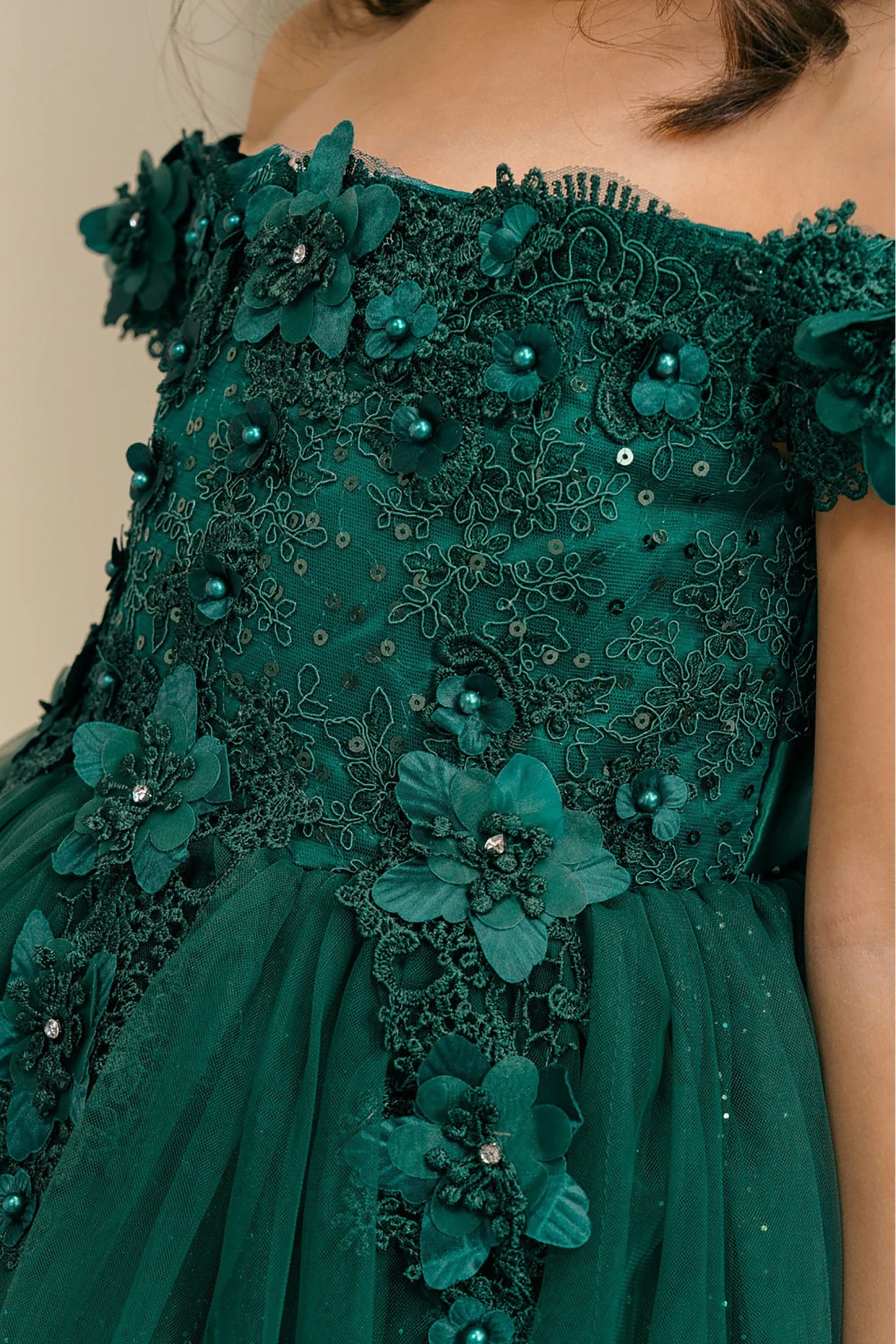 Close-up of a green floral flower girl dress with intricate details.