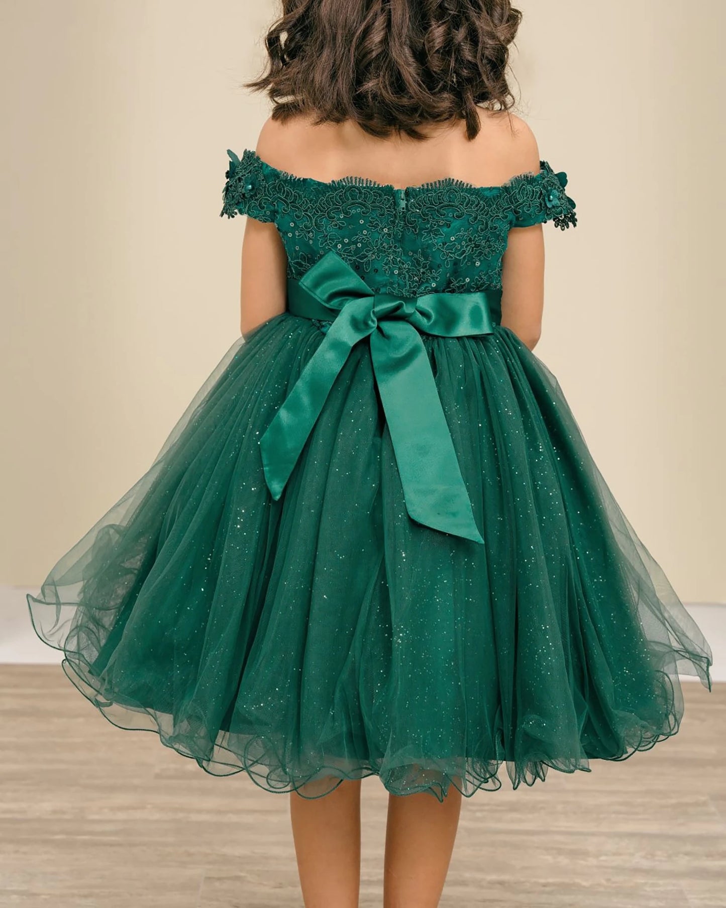 Green off-shoulder flower girl dress with a large bow.