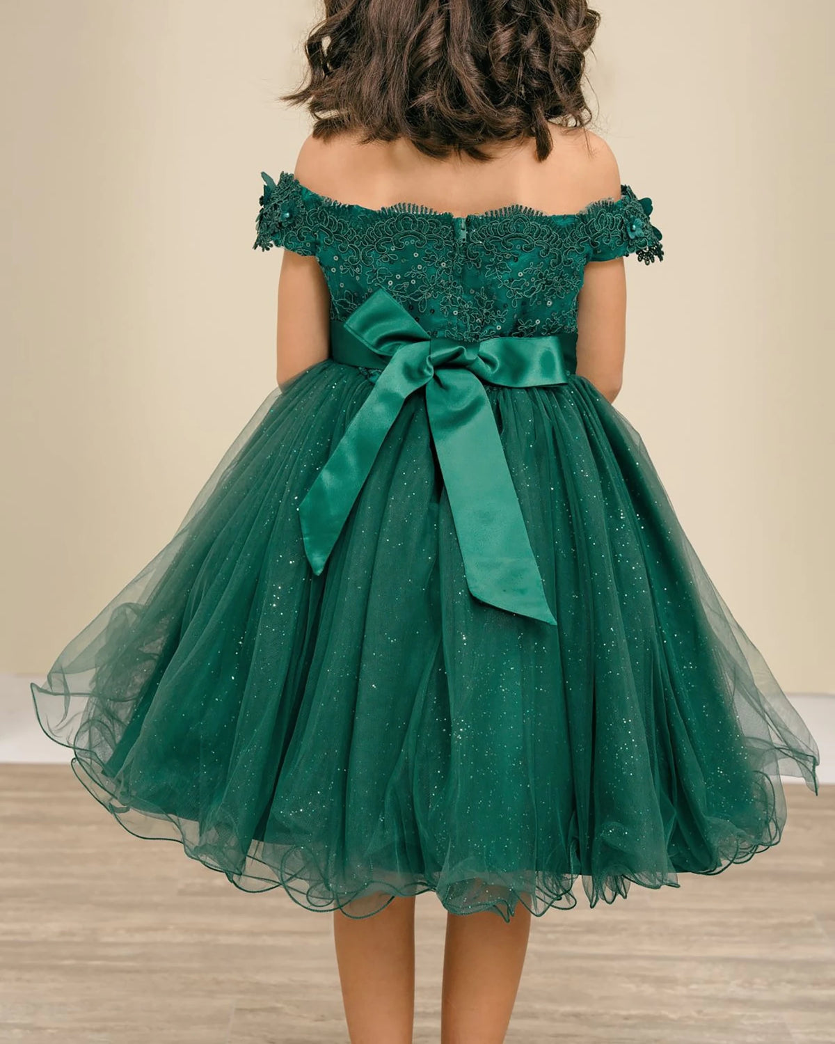 Green off-shoulder flower girl dress with a large bow.