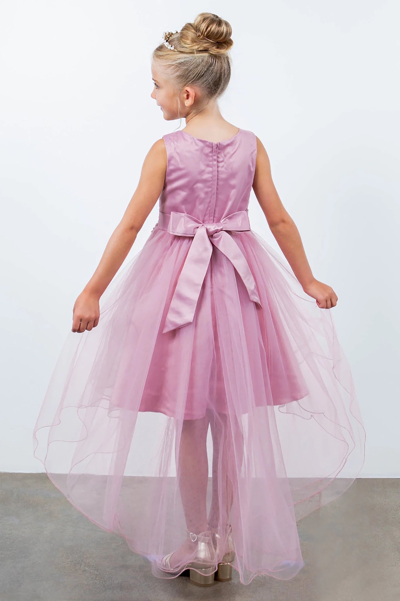 Back view of dusty rose sleeveless high-low tulle flower girl dress with lace-up closure, pearl trim neckline, rhinestone details, and cascading skirt.