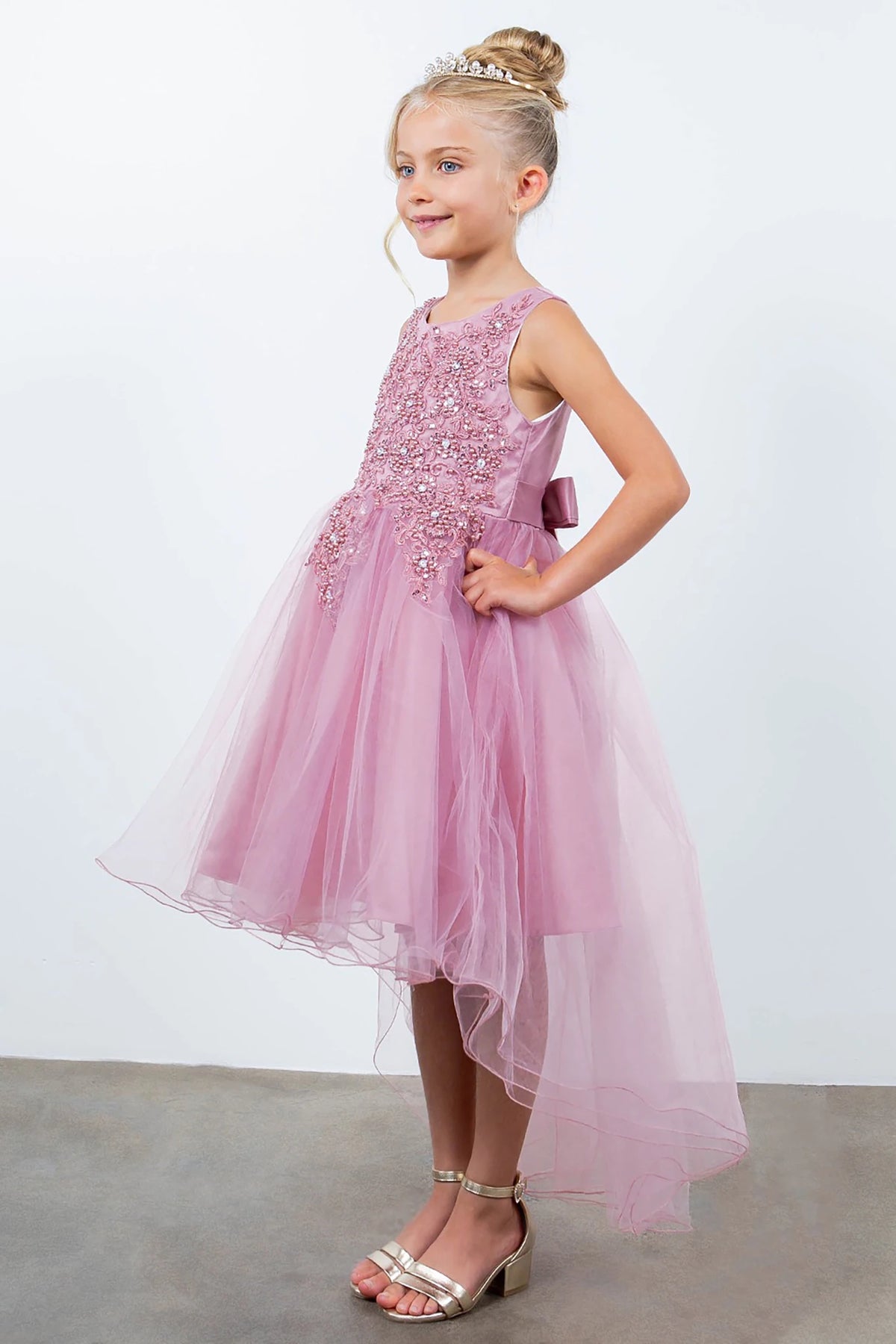 Side view of dusty rose sleeveless high-low tulle flower girl dress with lace detailing, pearl accents, rhinestone sparkle, and flowing layered skirt.