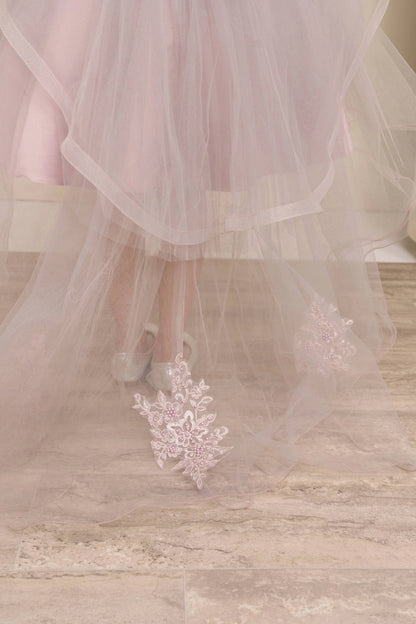 Displayed in a skirt detail, the Mauve flower girl dress has layered tulle hem and lace appliques on the trailing skirt.