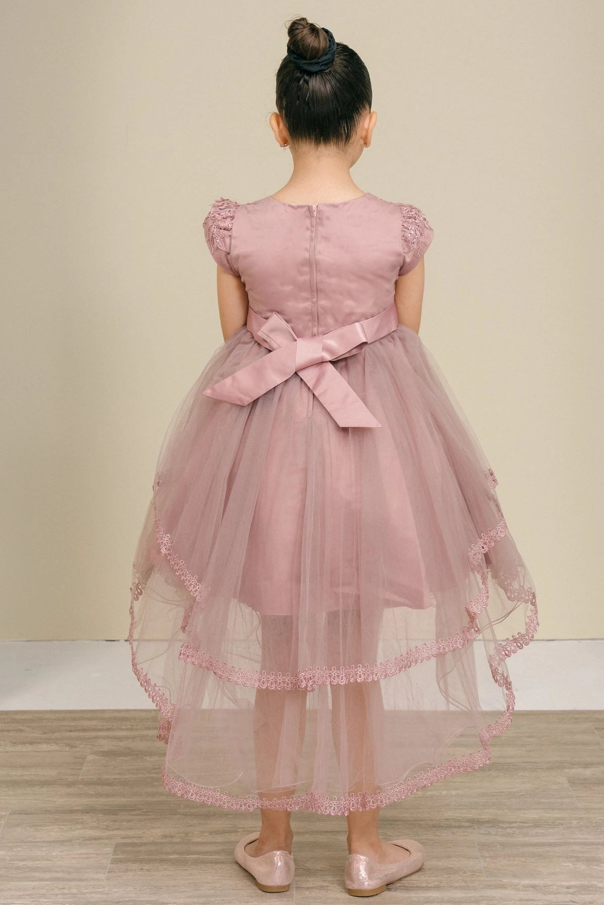 A Mauve flower girl dress showing back satin bow above the longer tulle hem.