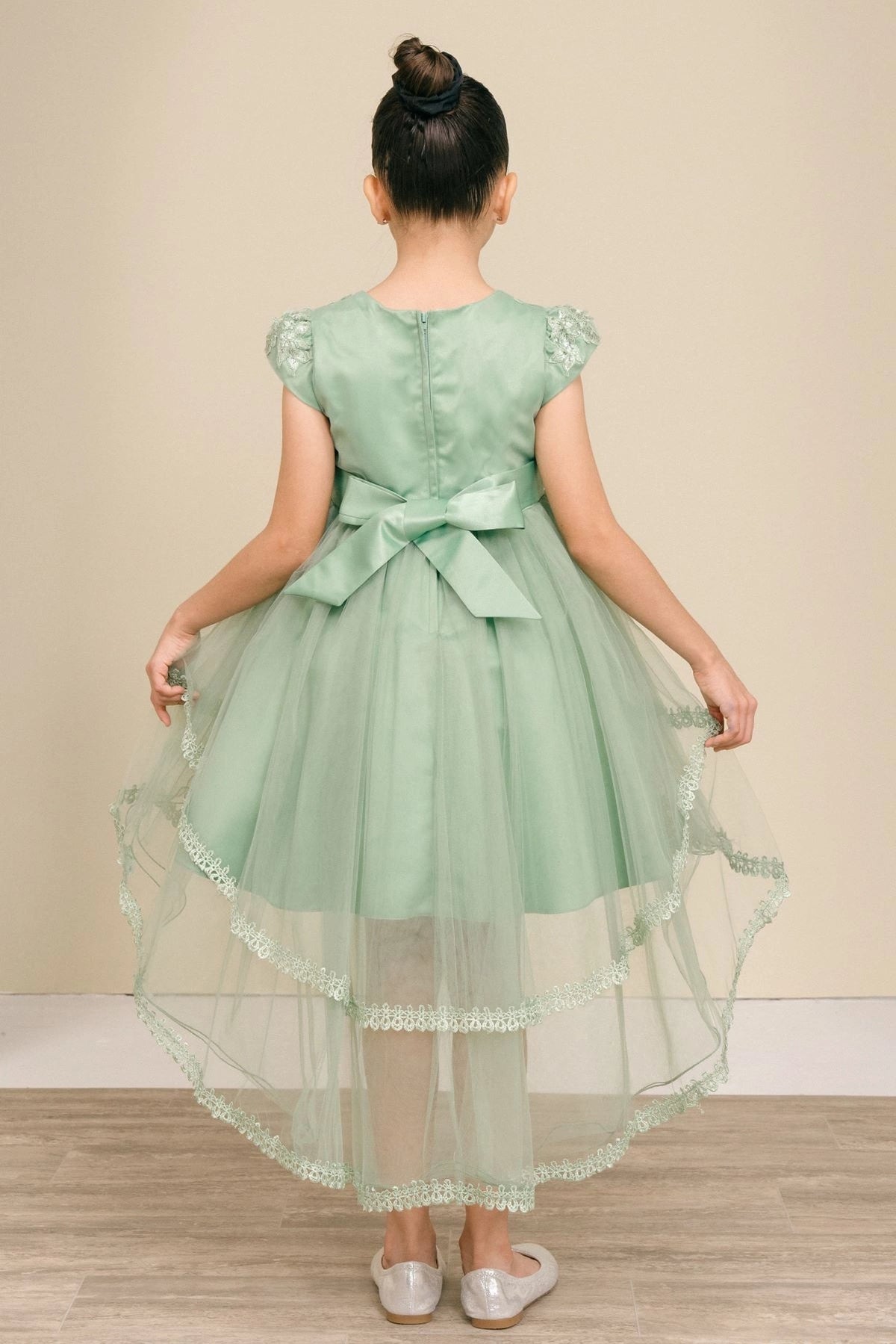 A Sage flower girl dress showing sash bow and long tulle hem at the back.