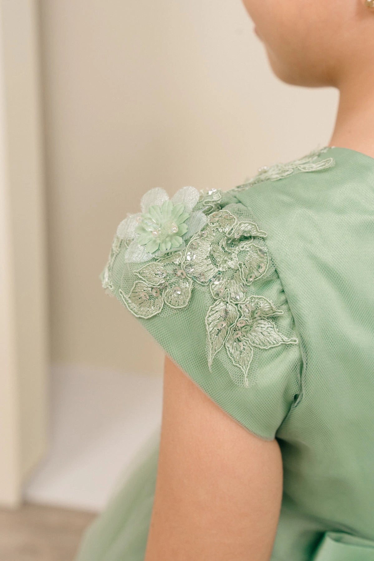 Notice the floral lace on a satin cap sleeve on this Sage flower girl dress.