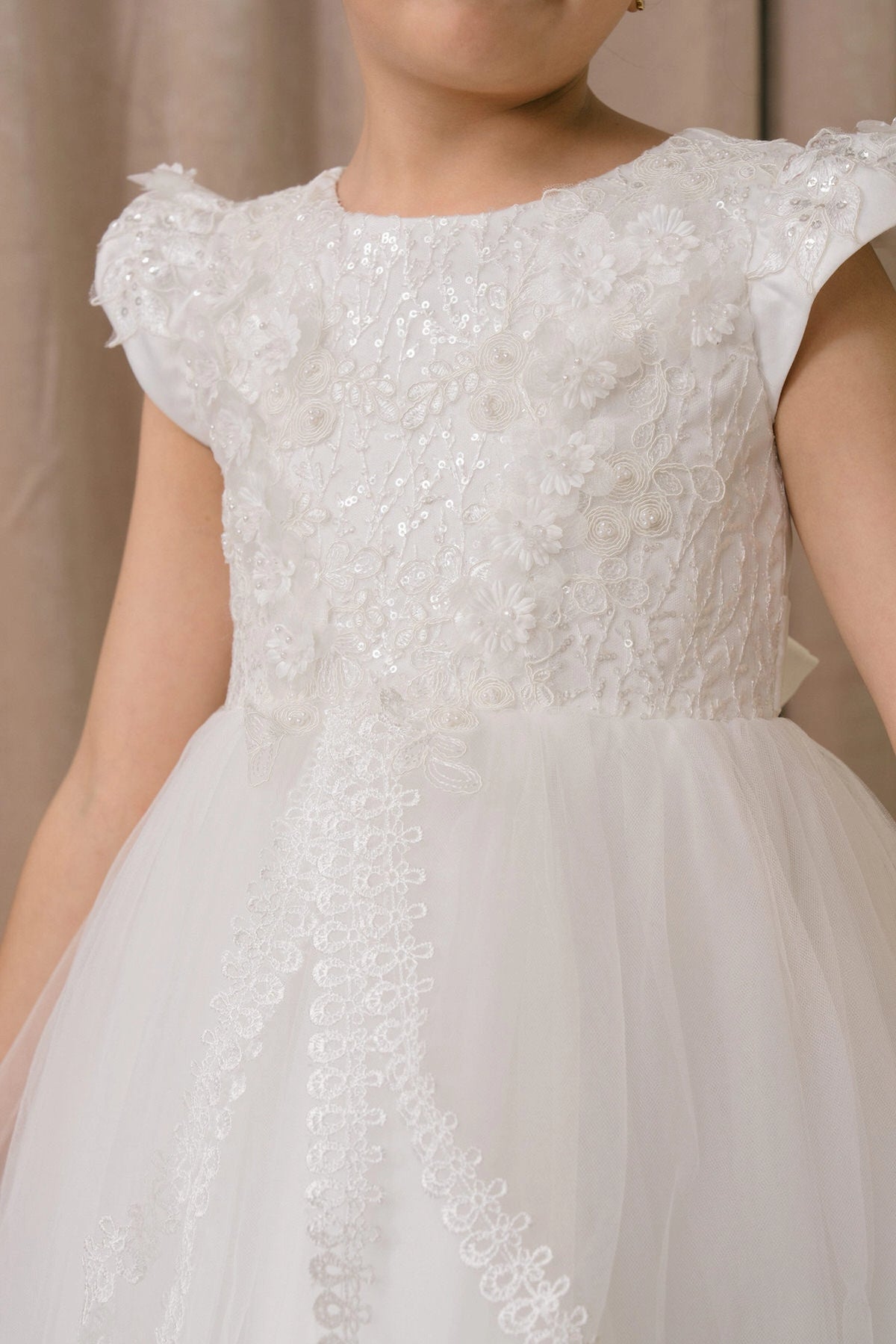 Visible on this White flower girl dress: floral lace across the cap-sleeve bodice.