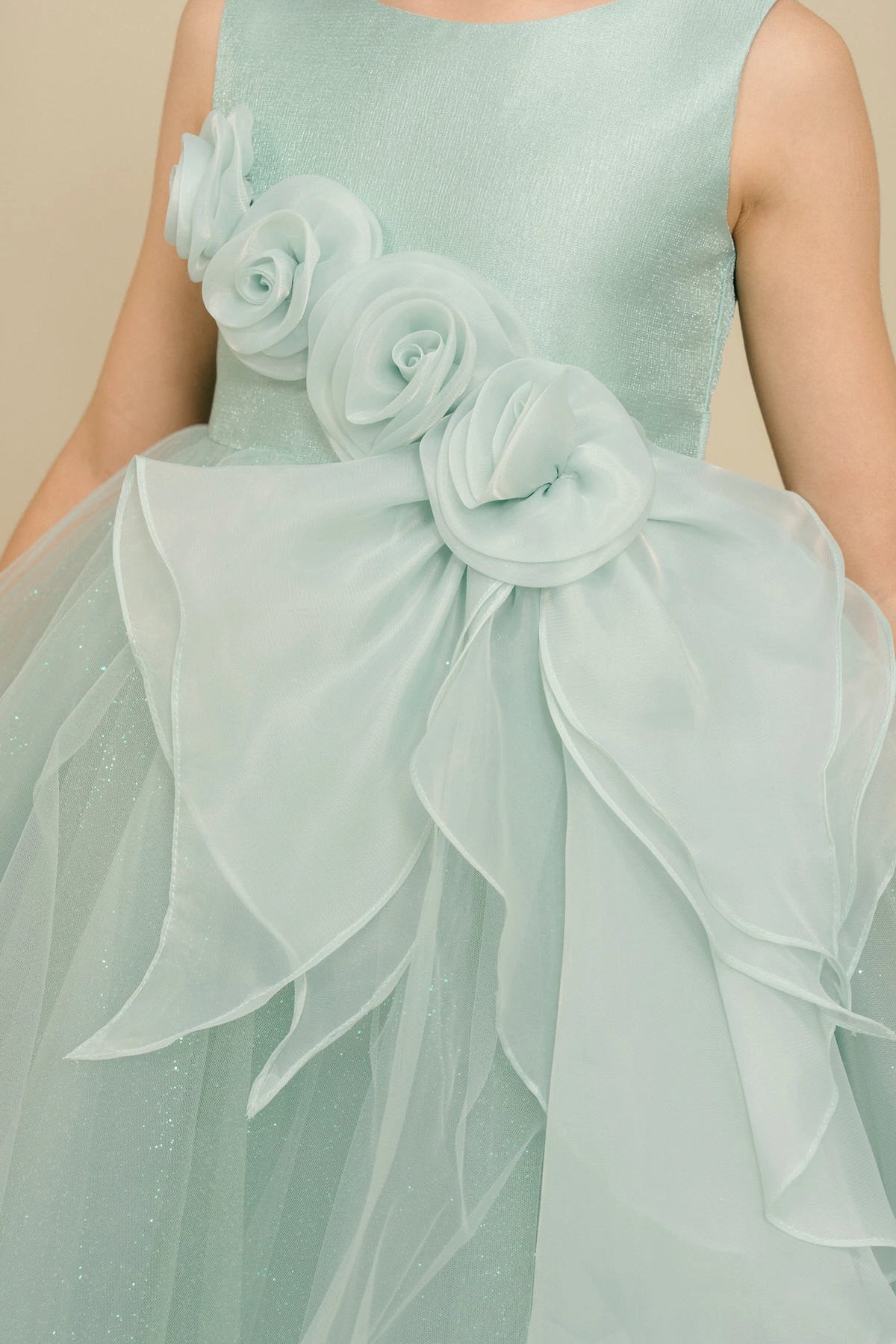 Details of the Sage flower girl dress include fabric roses above the draped ruffle.