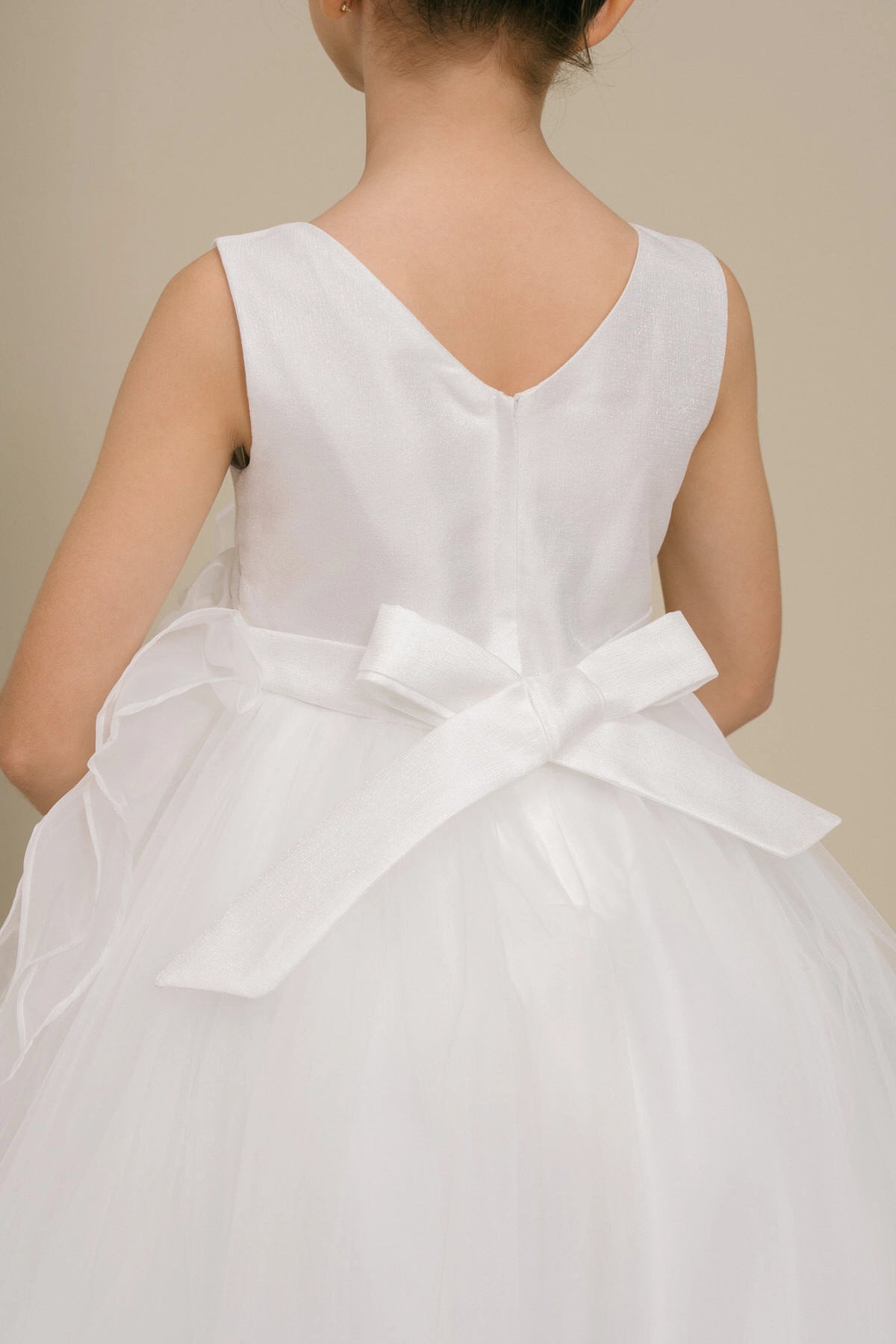 Details of the White flower girl dress include V neckline and satin bow at the back.