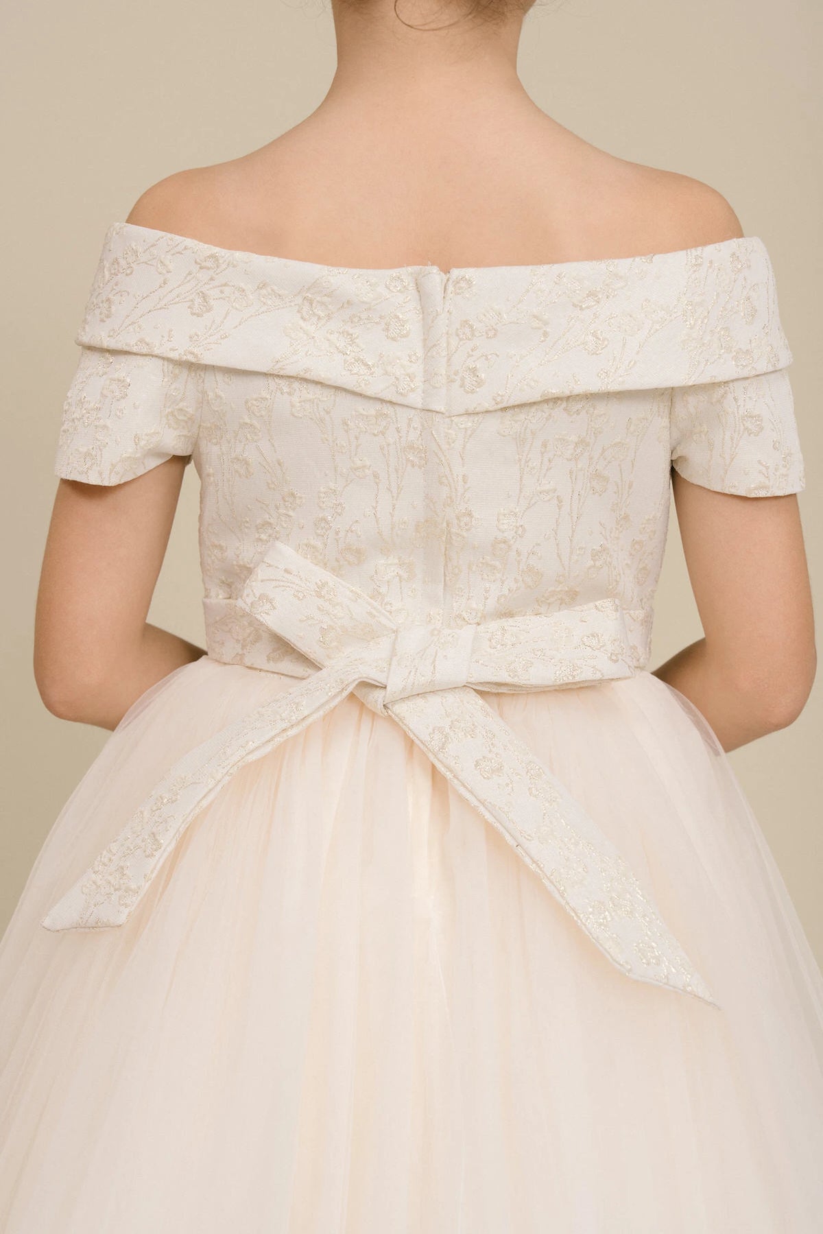 Detailed by a folded off-shoulder neckline, the Champagne kids party dress reveals its construction.