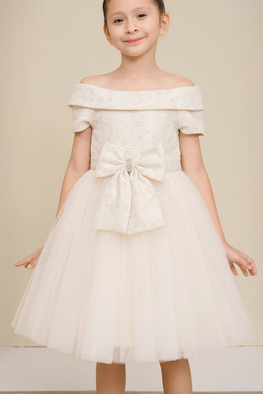 Accented a folded off-shoulder neckline adds character to this Champagne kids party dress.