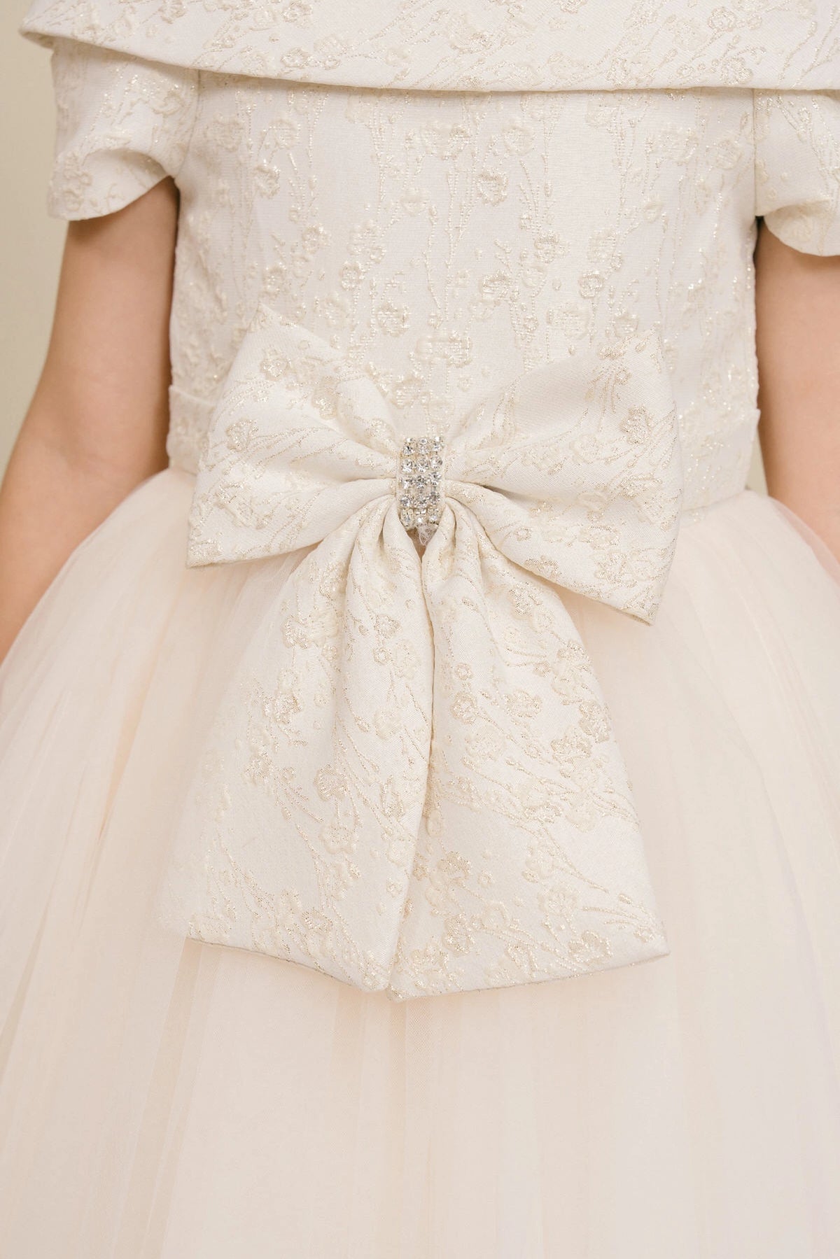 Finished details of a large waist bow distinguish the Champagne kids party dress.