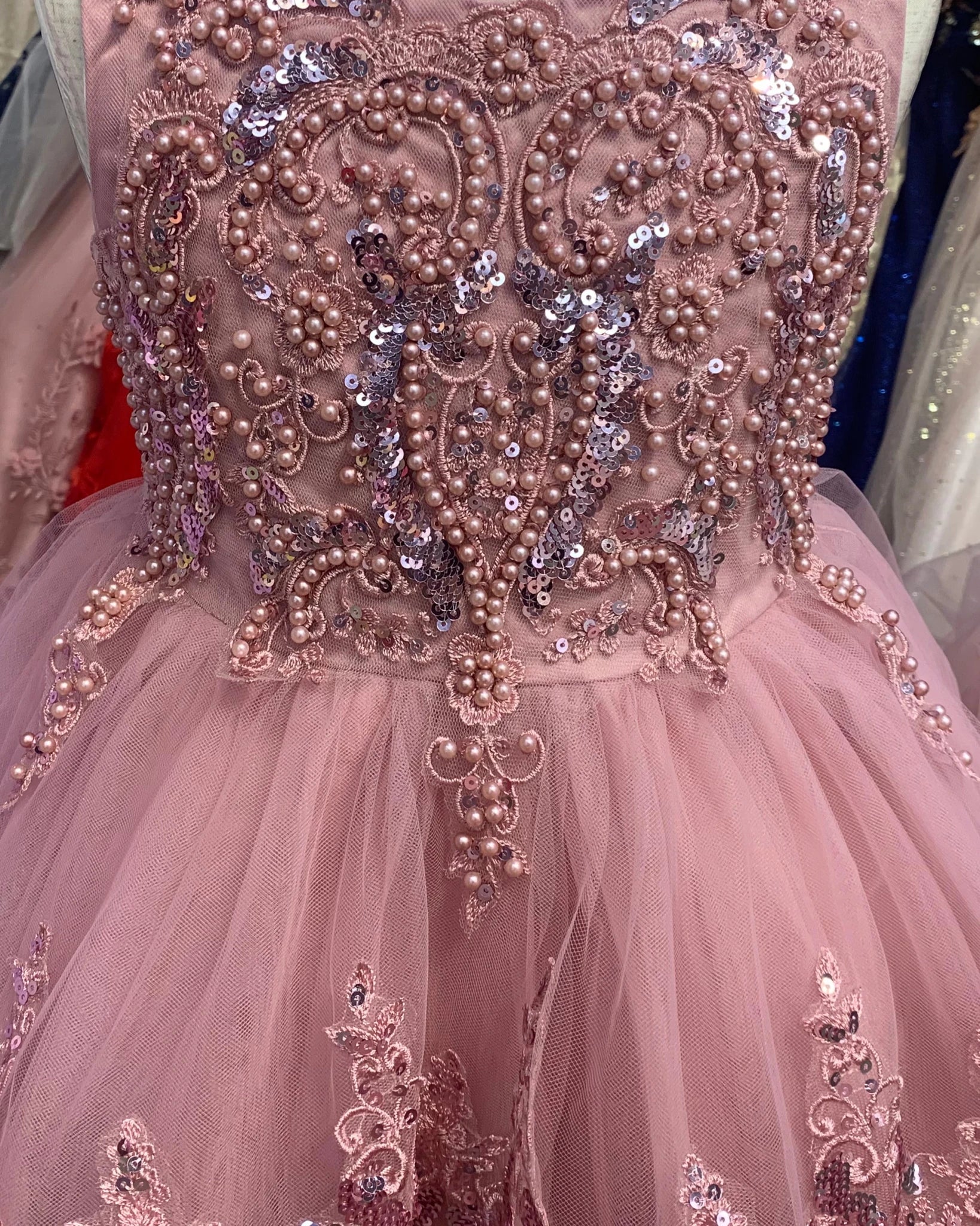 Close-up of a pink flower girl dress with intricate bead and sequin detailing.