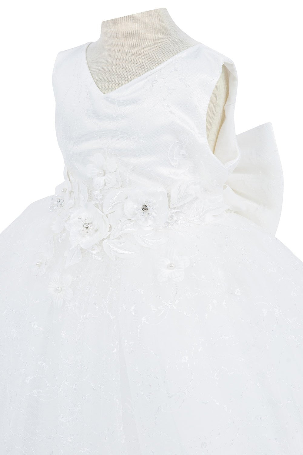 Close-up front view of white flower girl dress showing applique detail and shimmering embellishments.