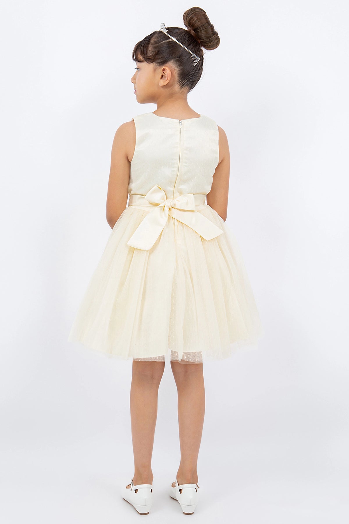 A Champagne flower girl dress showing back sash bow and zipper.