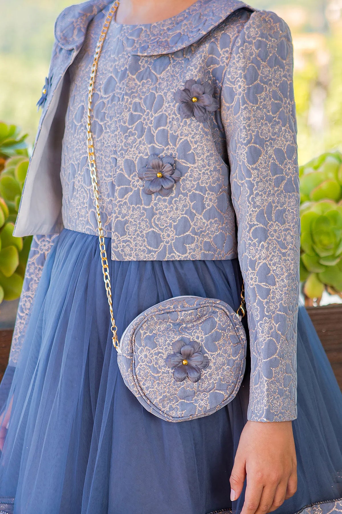 Detailed by a cropped matching jacket, the Royal Blue kids party dress reveals its construction.