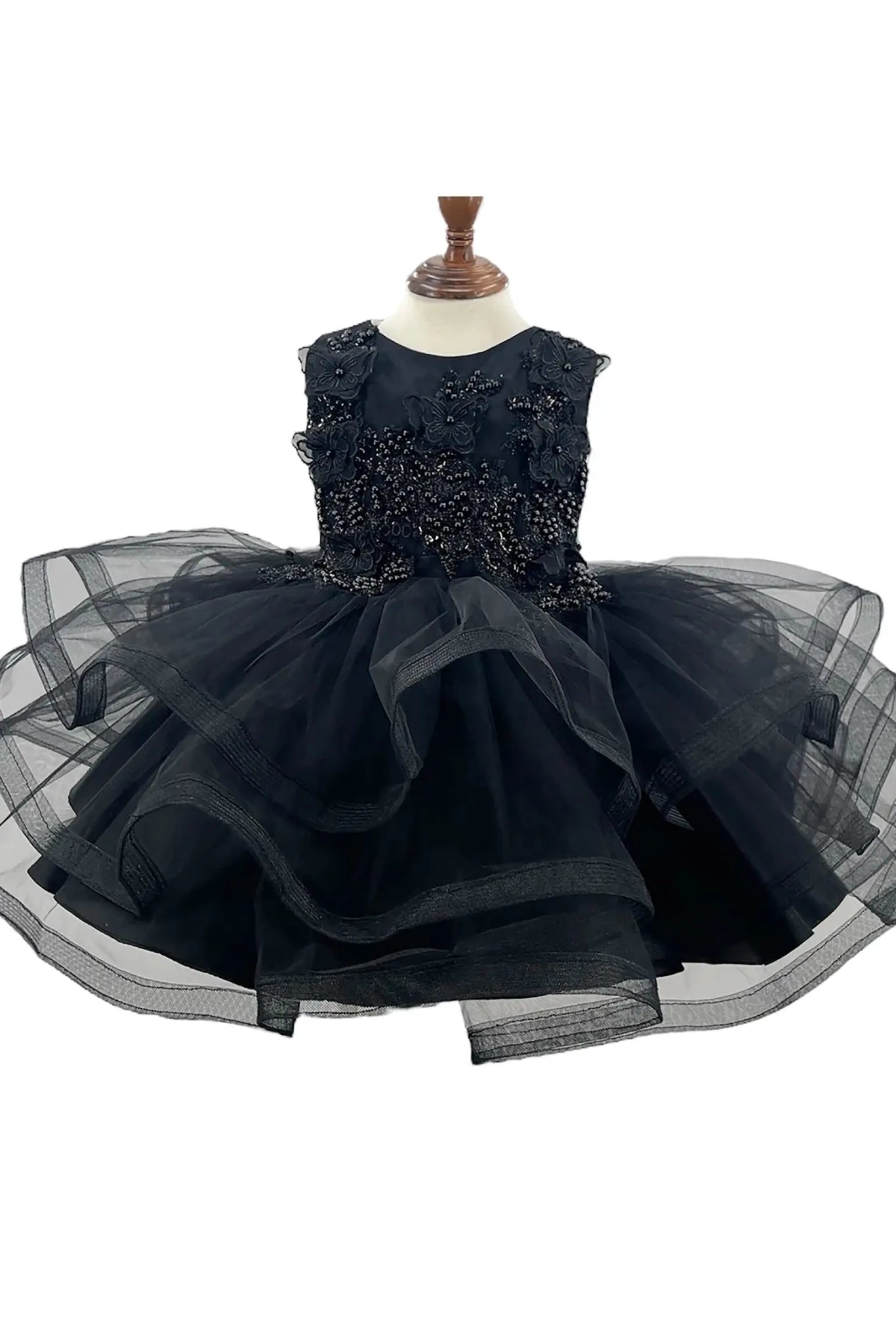 Front-facing in black multi-layered tulle 1st birthday party flower girl dress with butterfly accents and pearl embellishments on bodice.