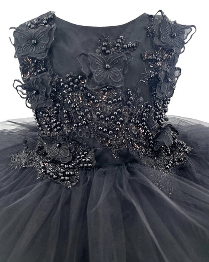 Detailed view highlights black flower girl dress with floral and butterfly embellishments.