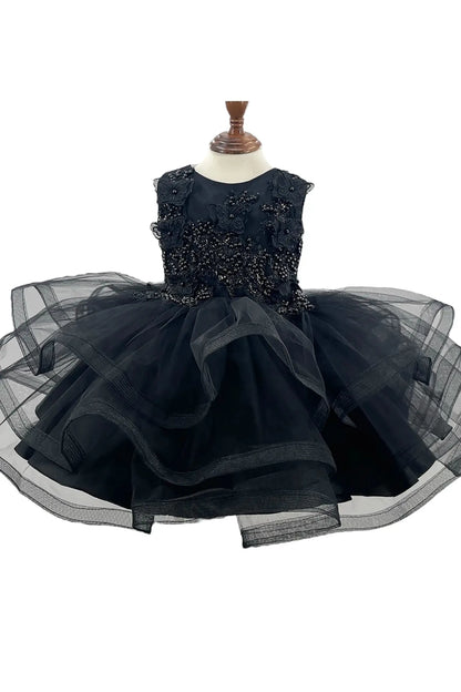 Front-facing in black multi-layered tulle 1st birthday party dress with butterfly accents and pearl embellishments on bodice