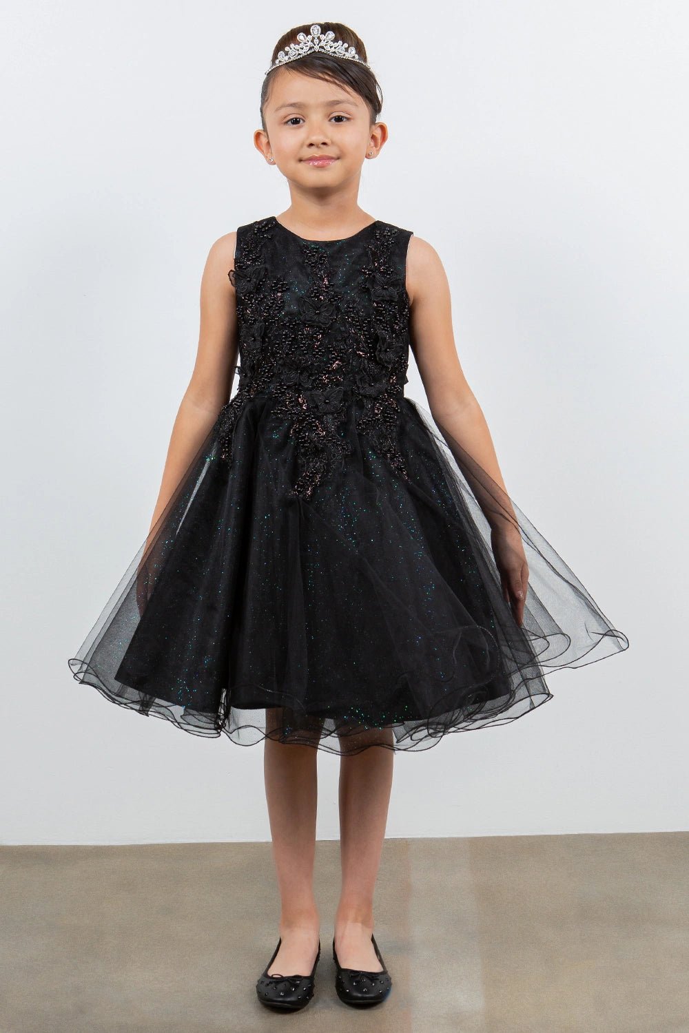 Displayed in a front view, the Black flower girl dress has floral lace bodice and layered tulle skirt with a wired hem.