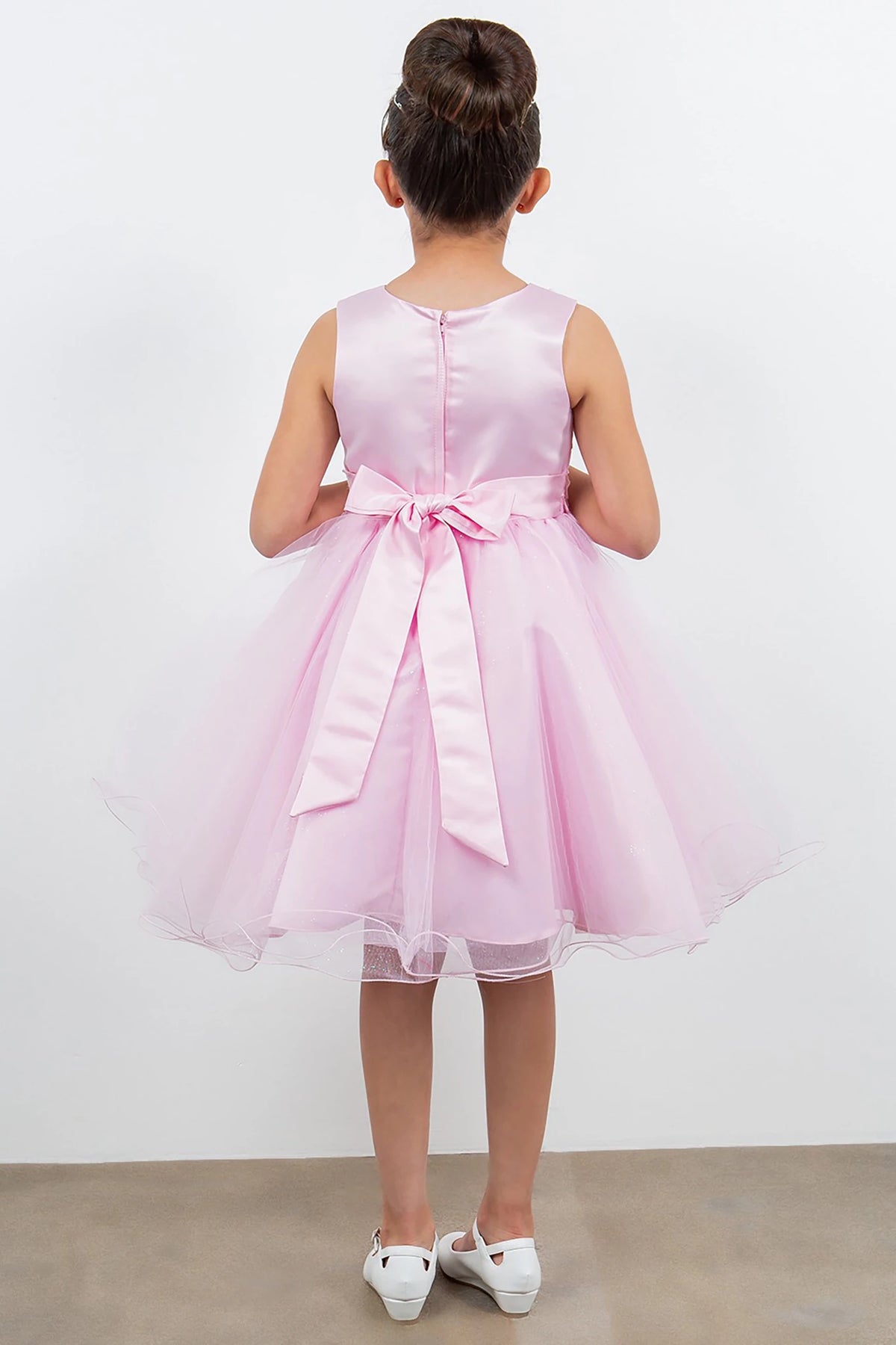 A pink flower girl dress with a bow at the back.