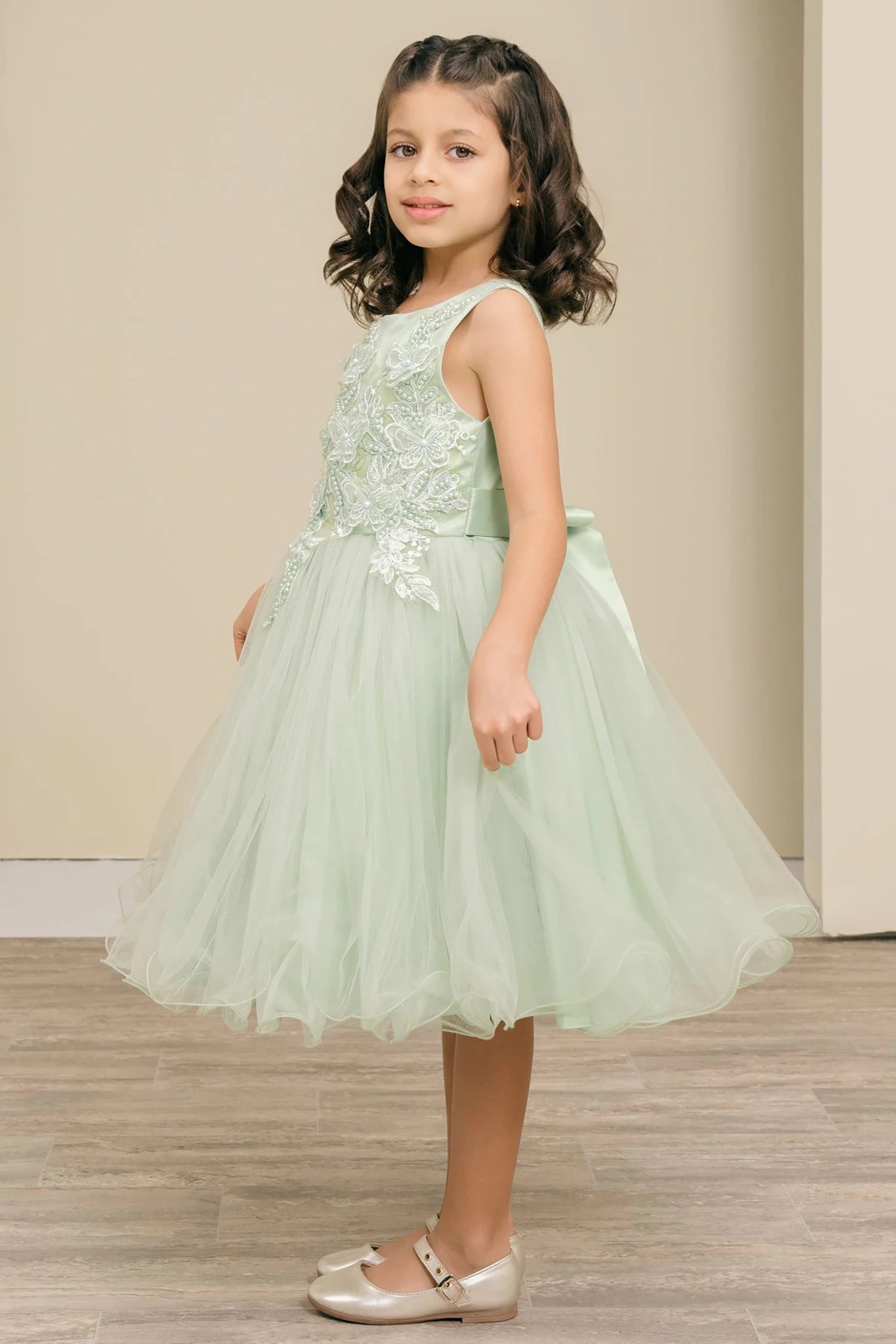 A sage green flower girl dress with floral details.