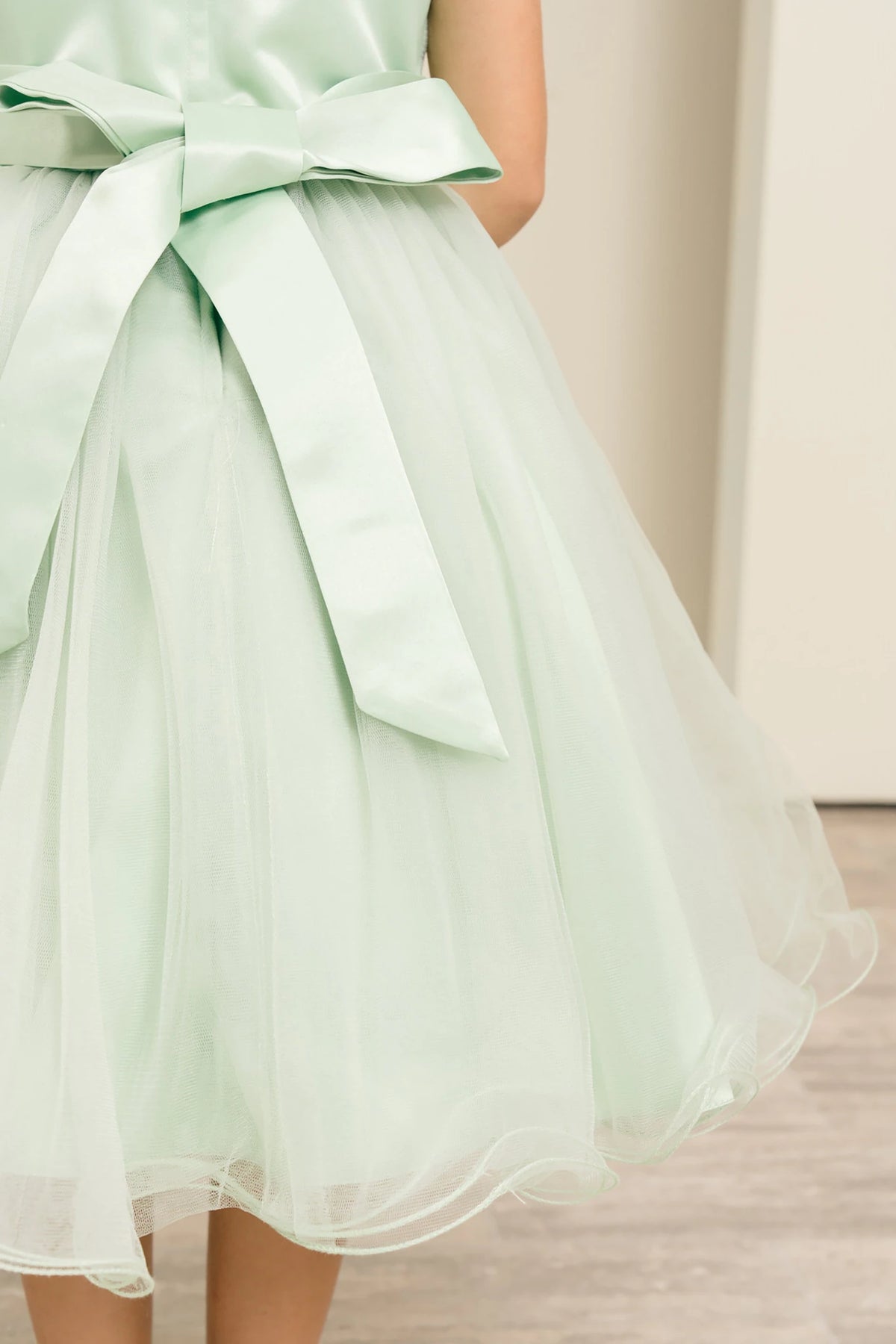 Sage green flower girl dress with a large bow detail.
