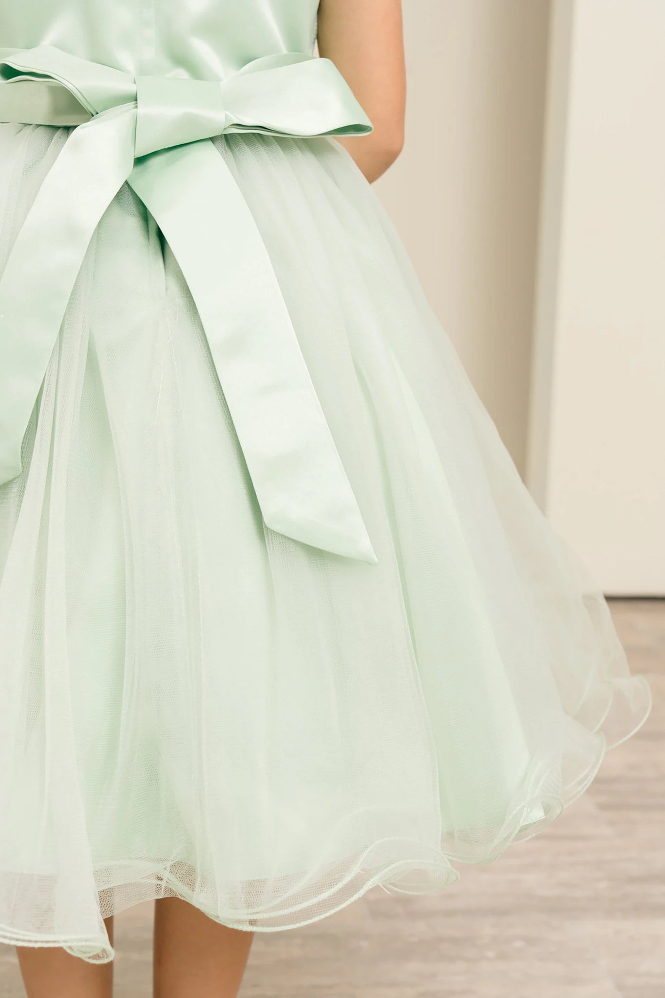 Sage green flower girl dress with a large bow detail.