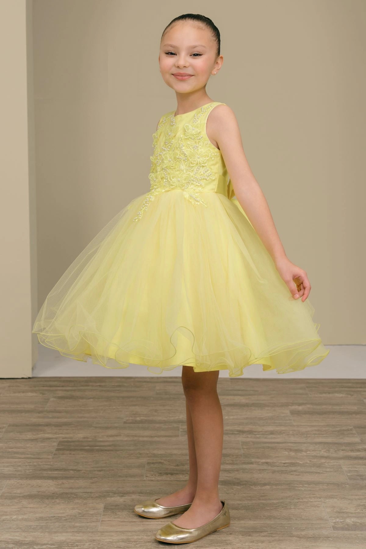 Shown in a front view, the Yellow flower girl dress has sleeveless floral bodice and flared tulle skirt.