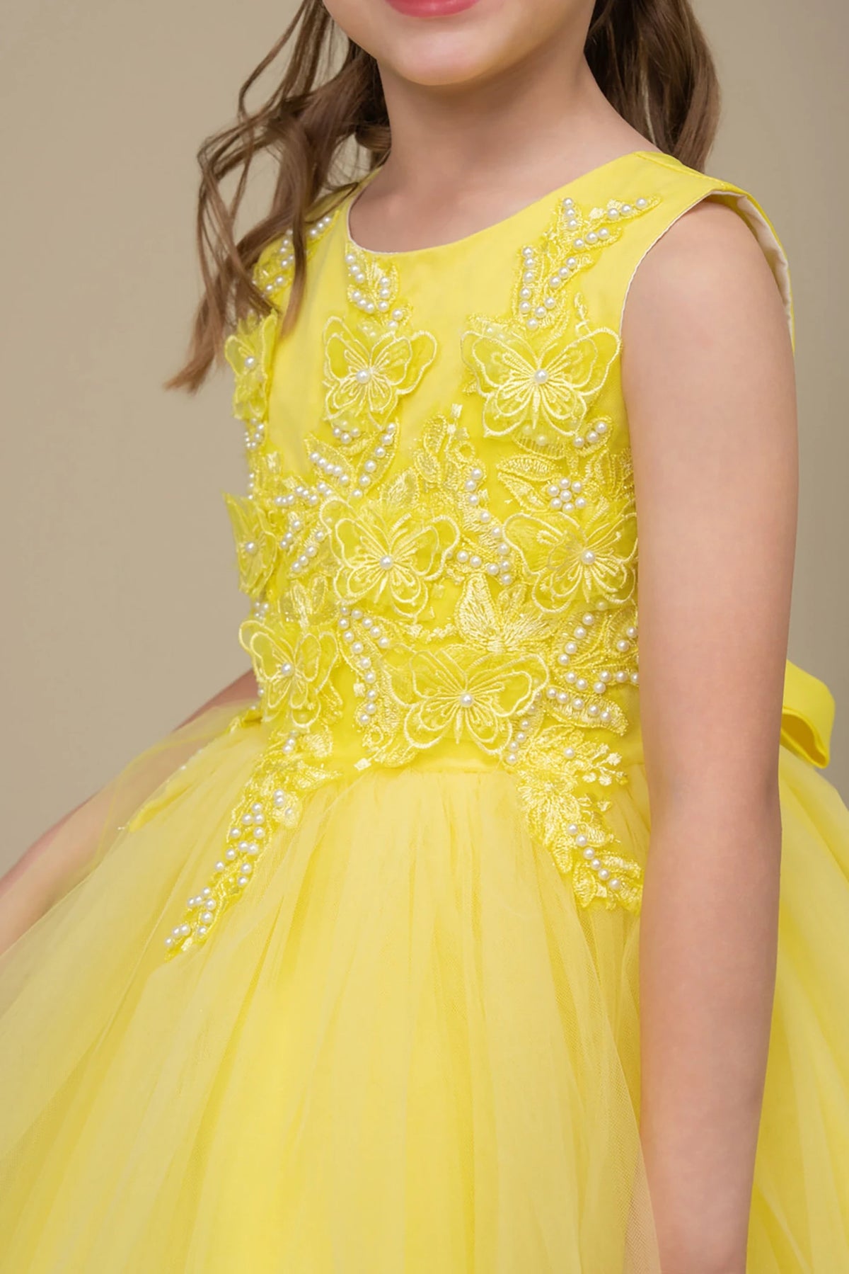Yellow flower girl dress with floral and butterfly embellishments.