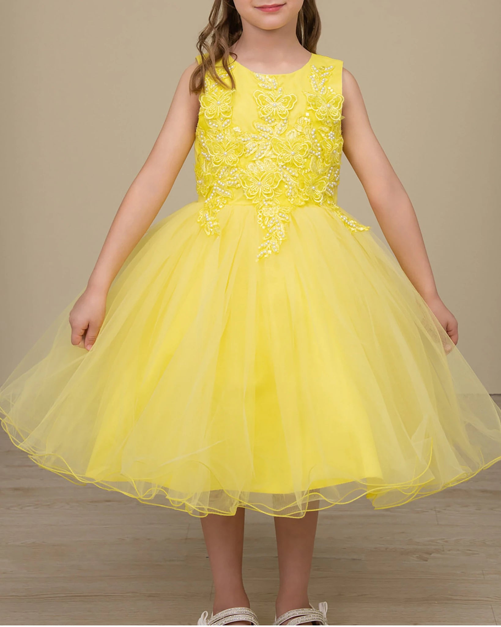 Yellow dress with floral lace top and tulle skirt on a neutral background