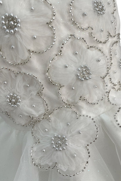 Close-up front view of ivory dress showing shimmering fabric and bow accent