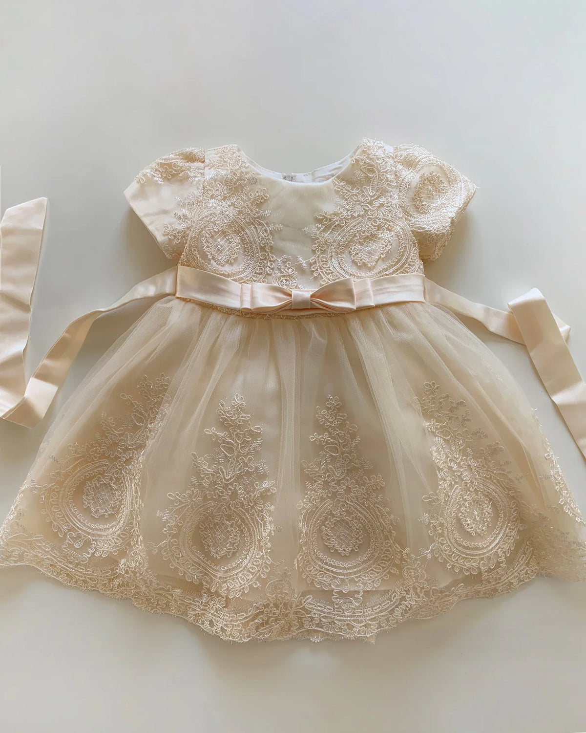 Champagne lace flower girl dress with a bow.