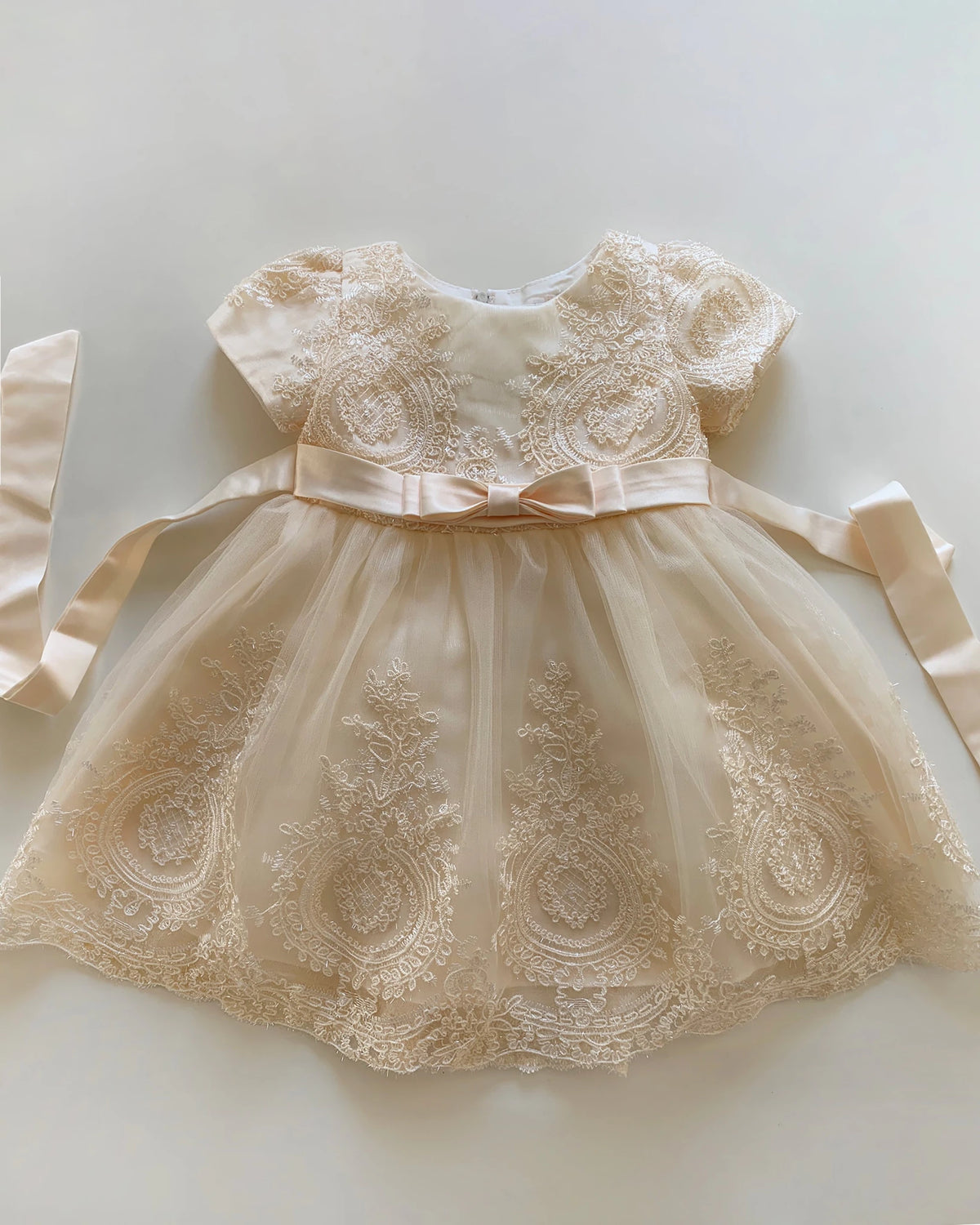 Champagne lace flower girl dress with a bow.