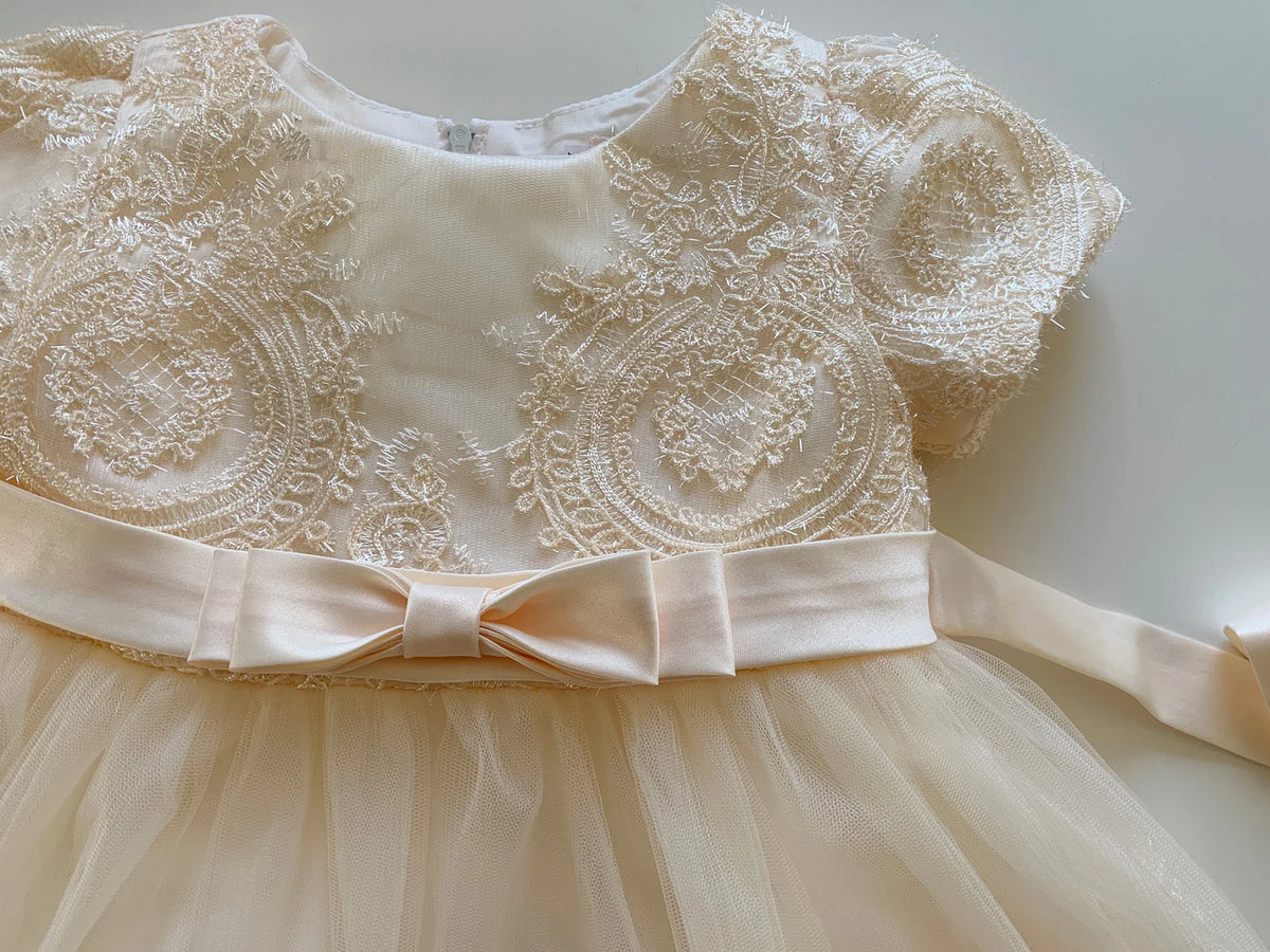 Champagne lace flower girl dress with a bow.