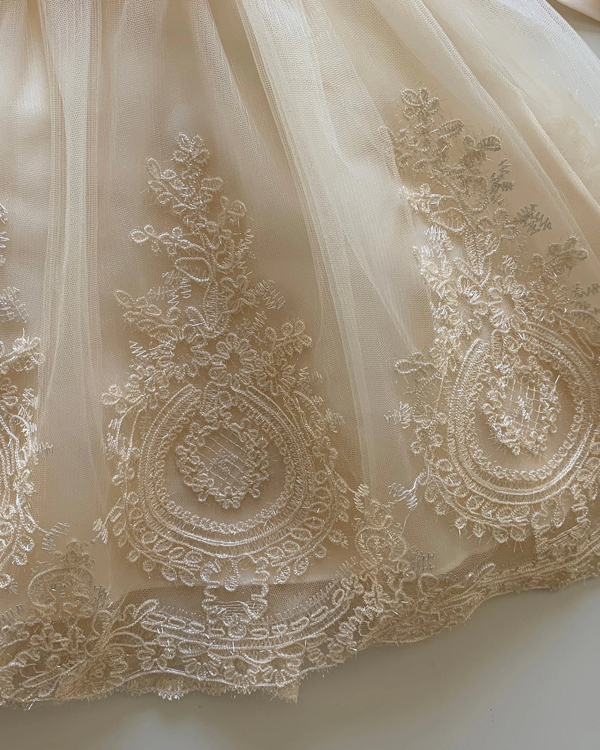 Close-up of intricate lace fabric with detailed patterns. Flower girl dress.