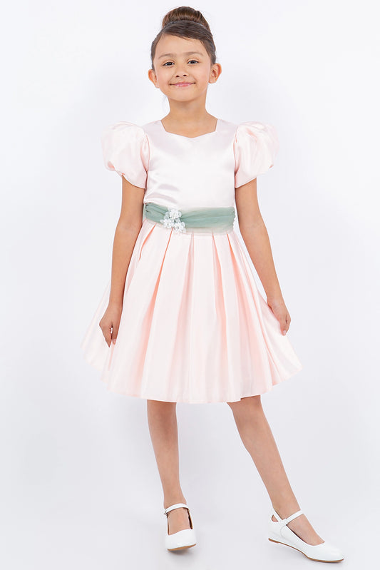 Blush flower girl dress features puff sleeves and contrasting waist sash.