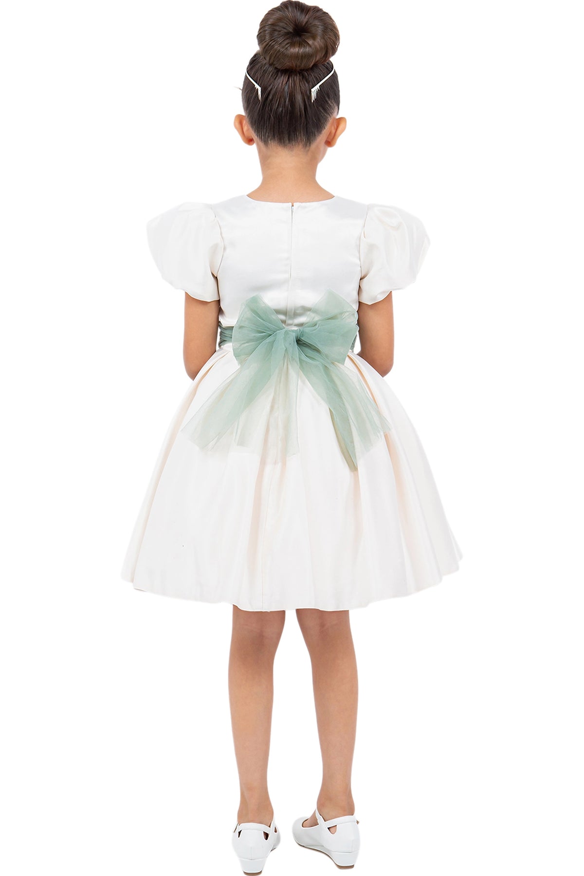 A Ivory flower girl dress showing large back bow beneath the puff sleeves.