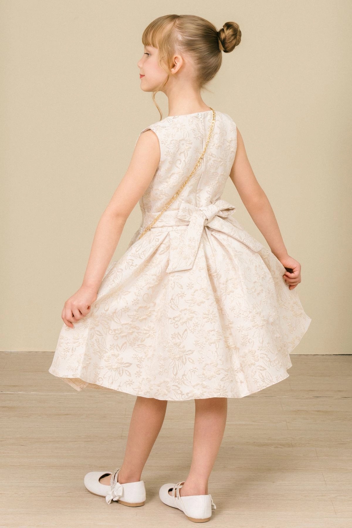 Finished details of a satin waist bow distinguish the Champagne kids party dress.