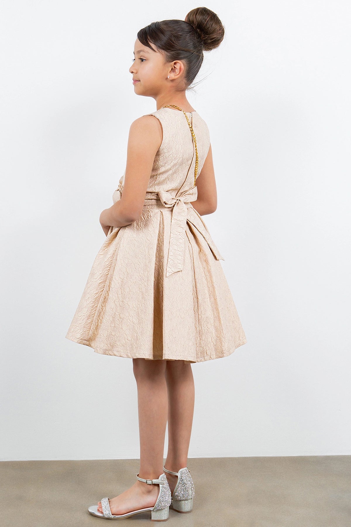Finished details of a back bow distinguish the Champagne kids party dress.