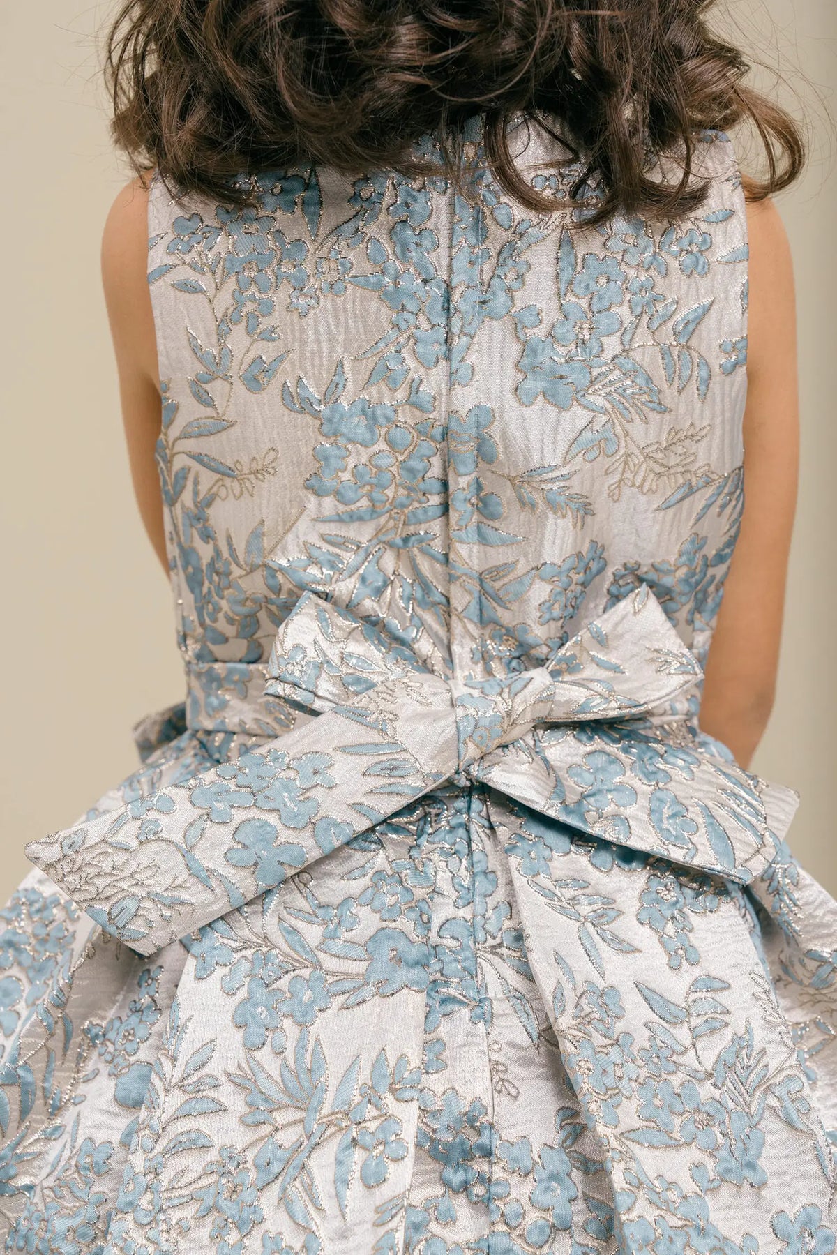 Detailed by a floral waist bow, the Dusty Blue kids party dress reveals its construction.
