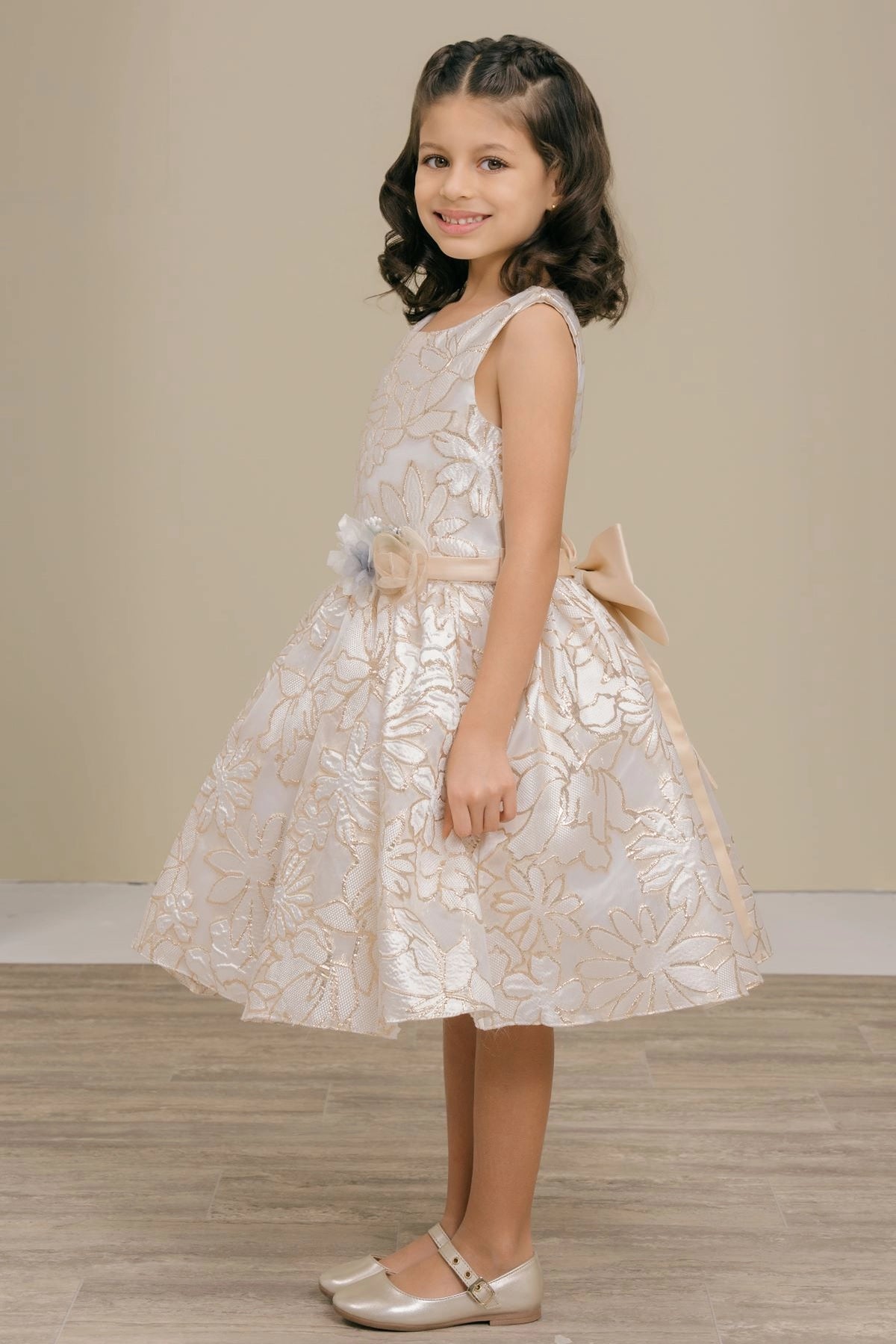 Featuring with a textured floral skirt, this Champagne kids party dress displays elegant detail.