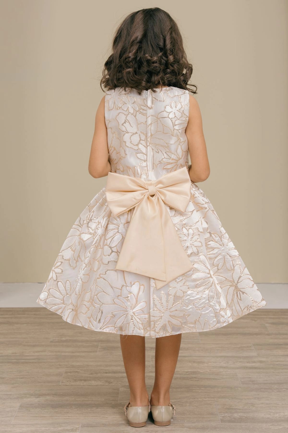Finished details of a large satin bow distinguish the Champagne kids party dress.