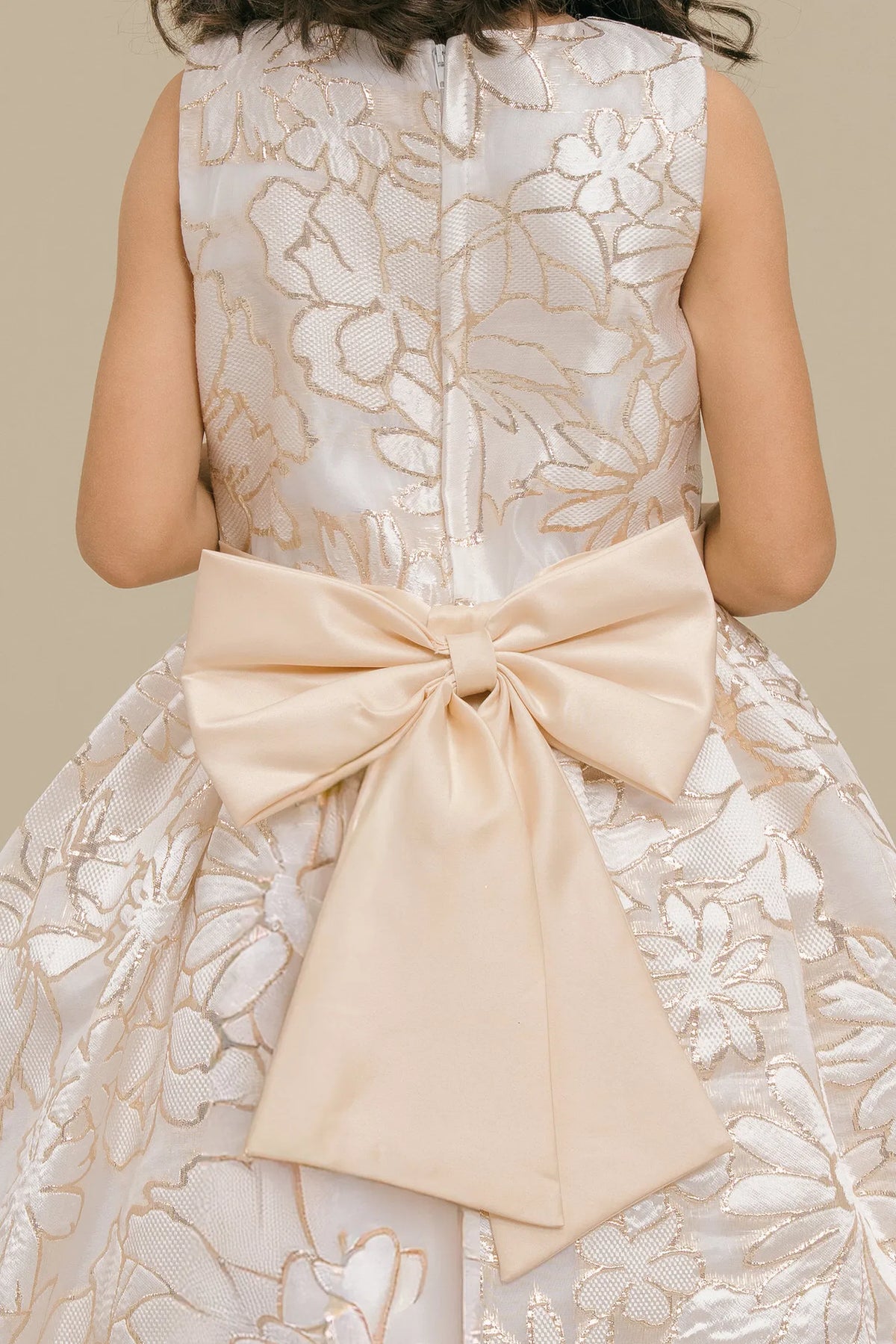 Detailed by a decorative floral waist accent, the Champagne kids party dress reveals its construction.
