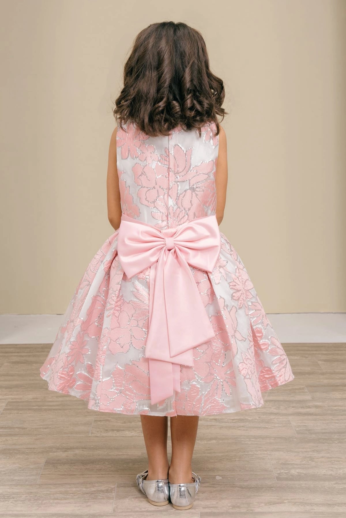 Detailed by a large satin bow, the Pink kids party dress reveals its construction.