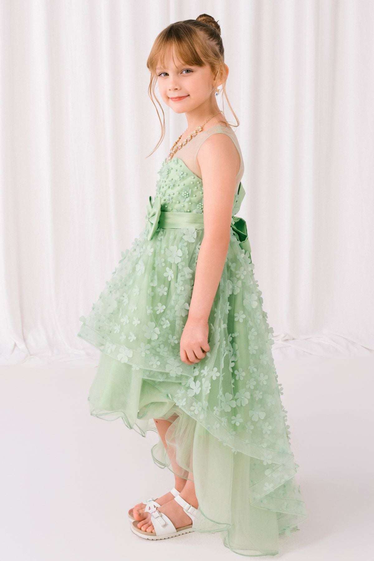 Sage flower girl dress front view with illusion bodice and hi-low 3D flower skirt.