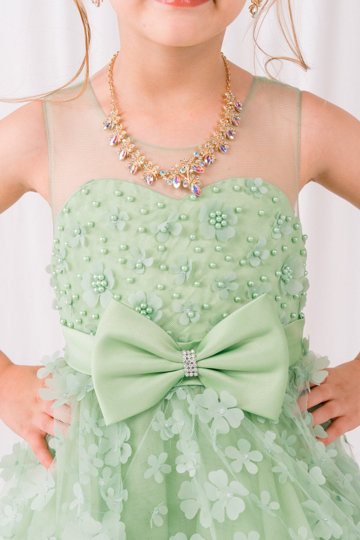 Close-up front view of sage flower girl dress showing 3D floral detail and bodice texture.