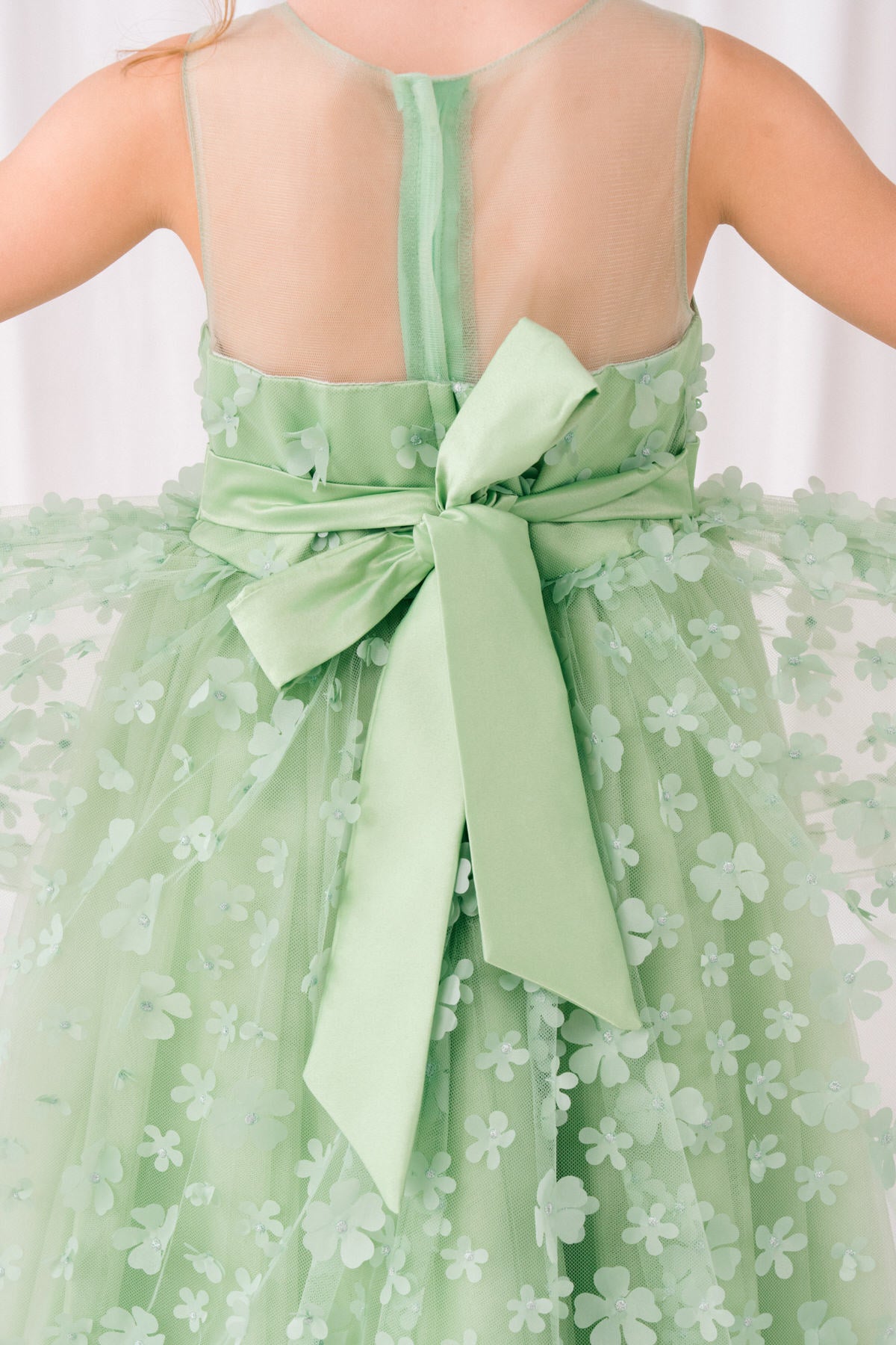 Sage flower girl dress side view highlighting hi-low silhouette and elegant structure.
