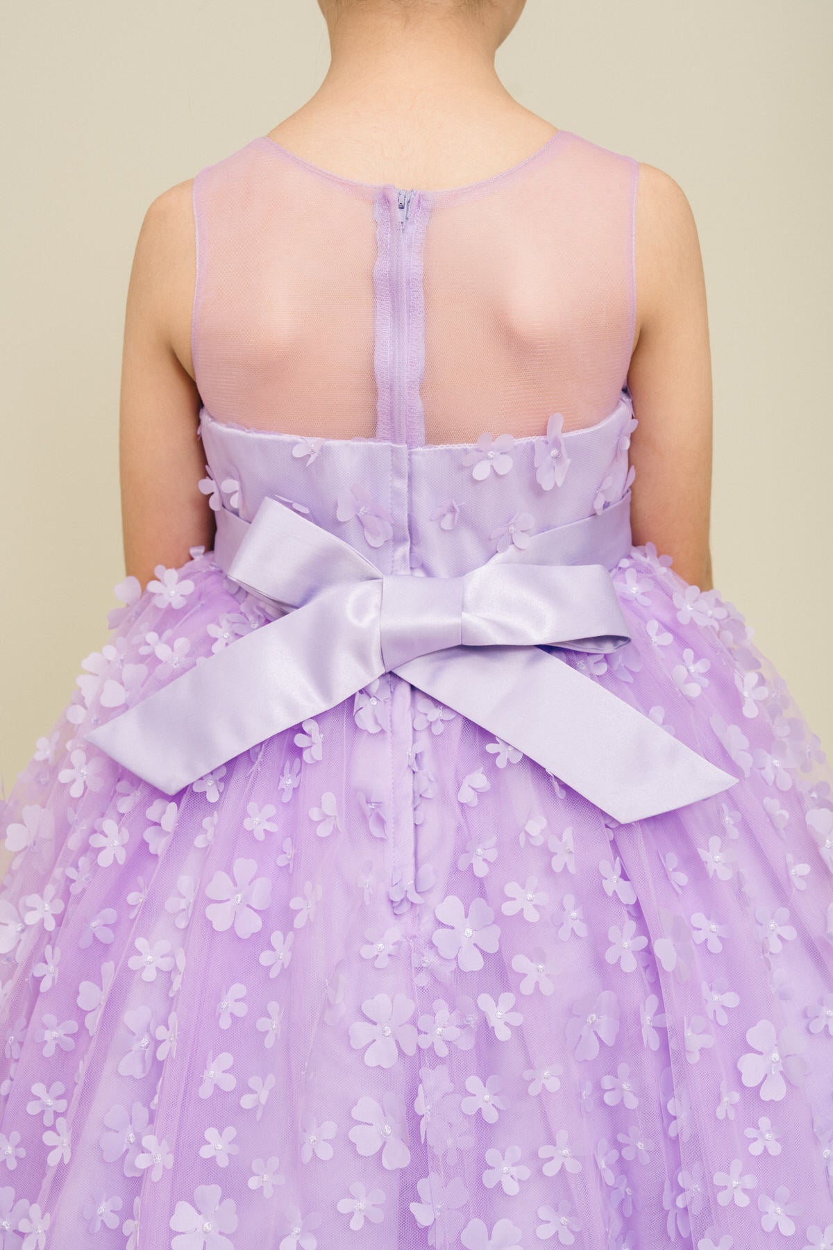 Close-up back view of lilac flower girl dress showing 3D floral detail and bodice texture.